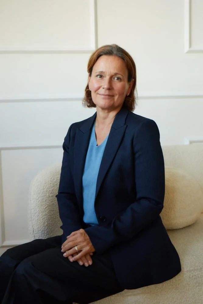 Judith smiles gently in a dark blue jacket.