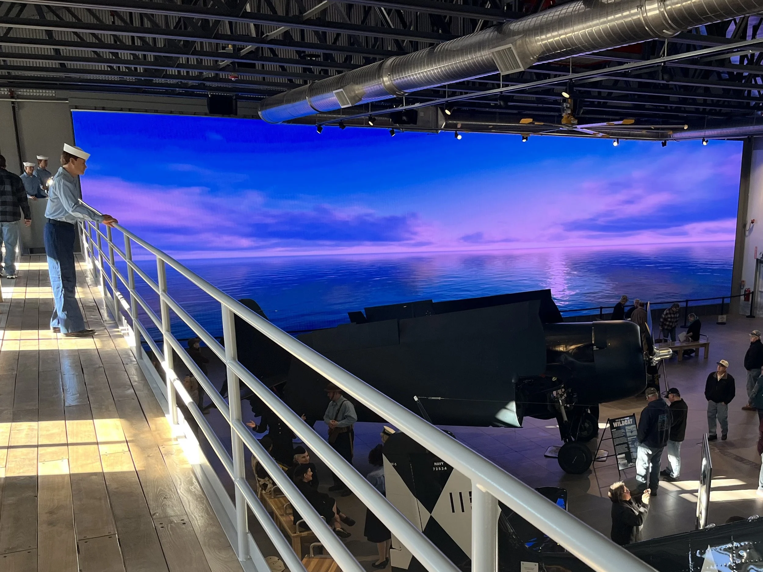 A large horizontal LED screen displaying a serene sunset with reflections over a body of water.