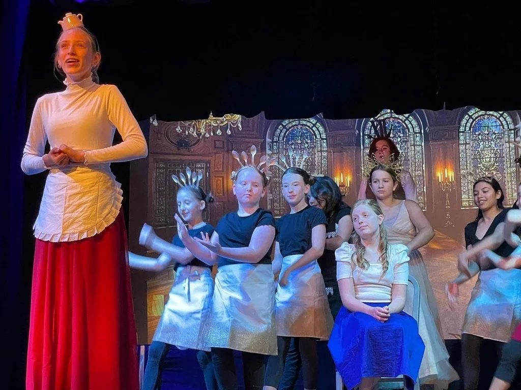 Children dressed as angels with gold halos on stage during a theatrical performance.