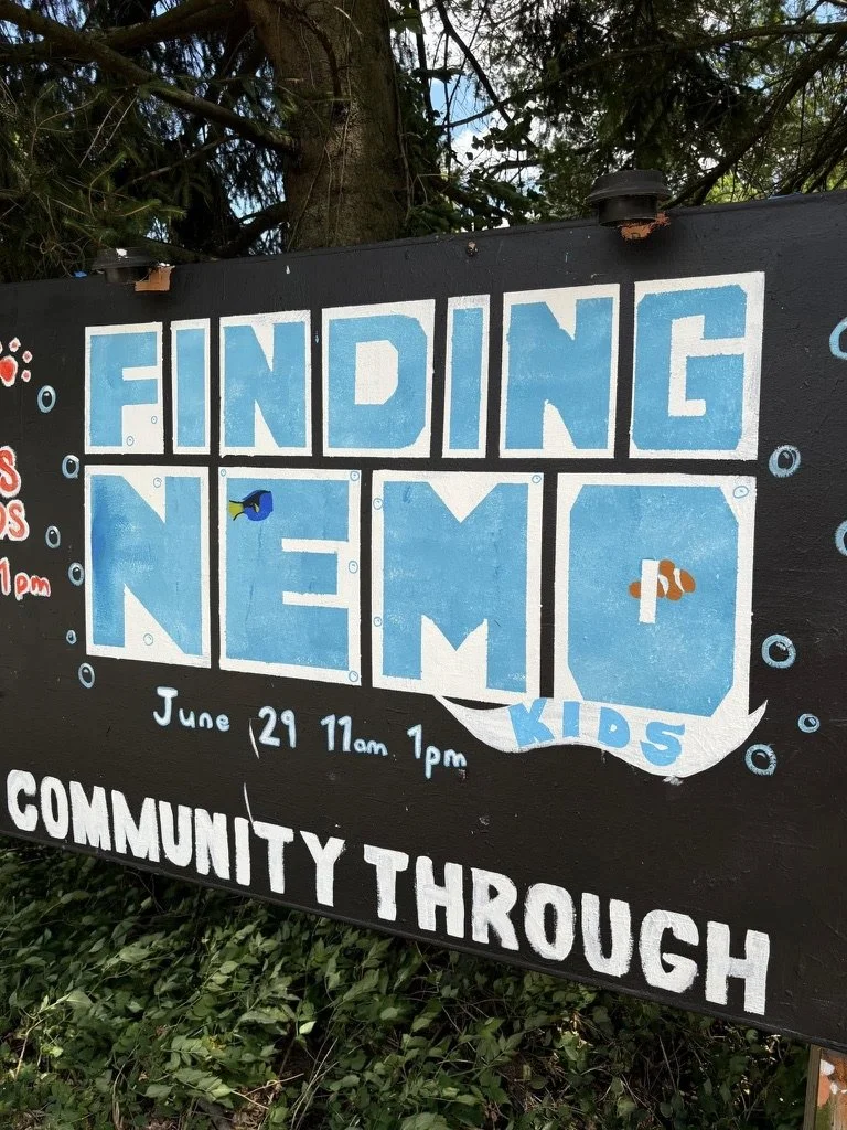 Sign for a kids' community outreach event titled 'Finding Nemo', scheduled for June 29 from 11 am to 1 pm, featuring underwater-themed decorations with fish illustrations.