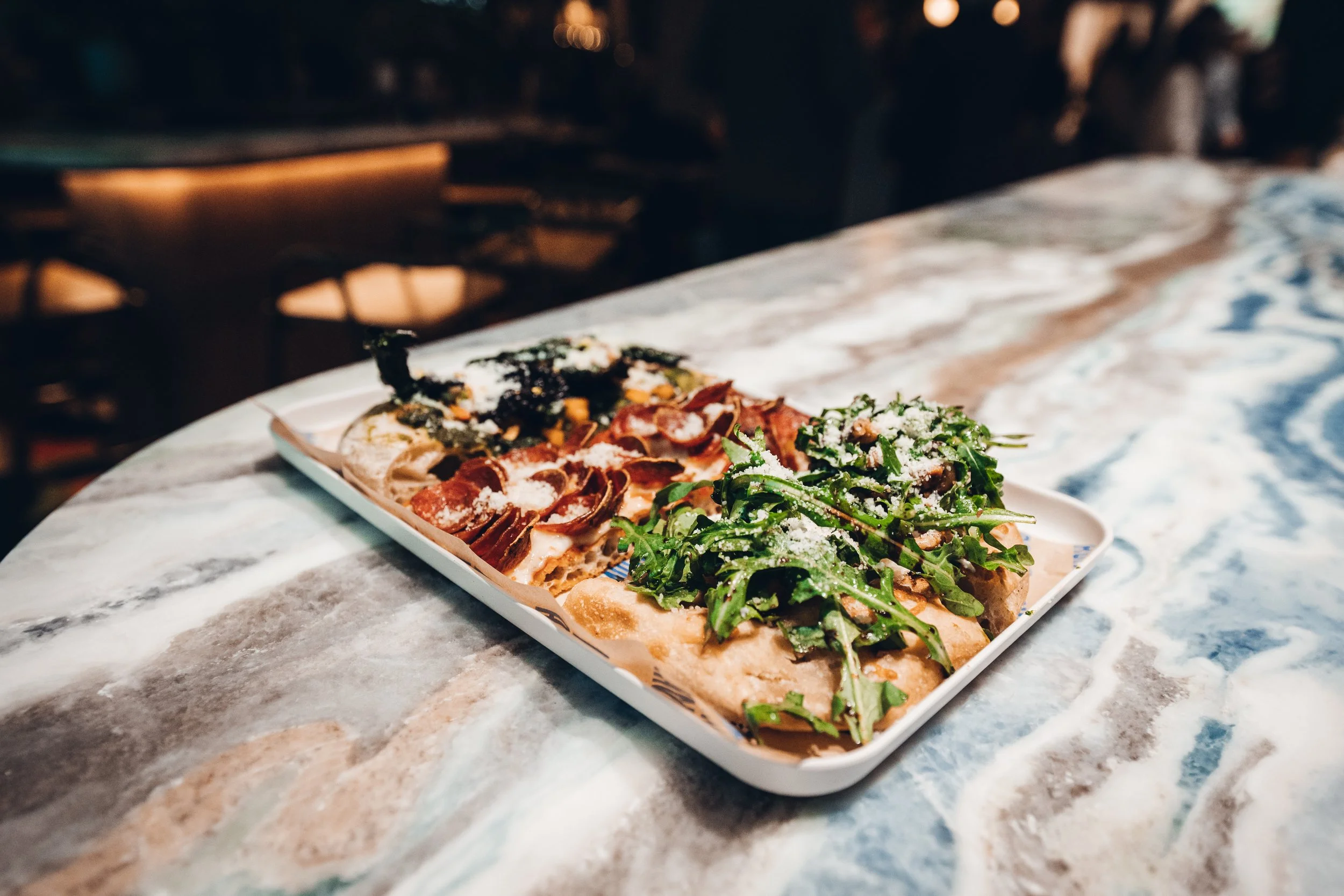 A plate of assorted pizza slices on a marble surface at a restaurant.