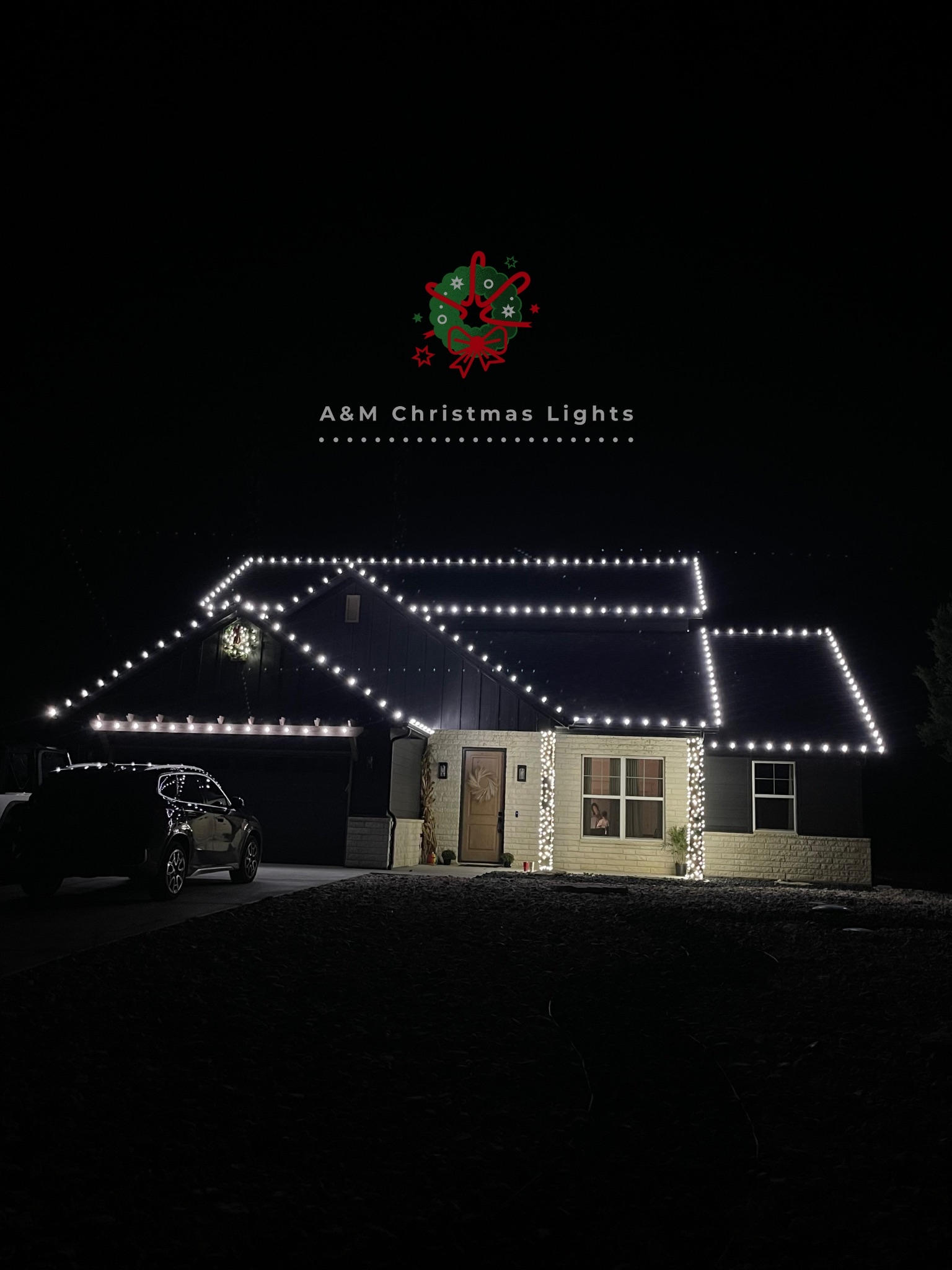 House decorated with white Christmas lights outlining the roof and front porch at night.