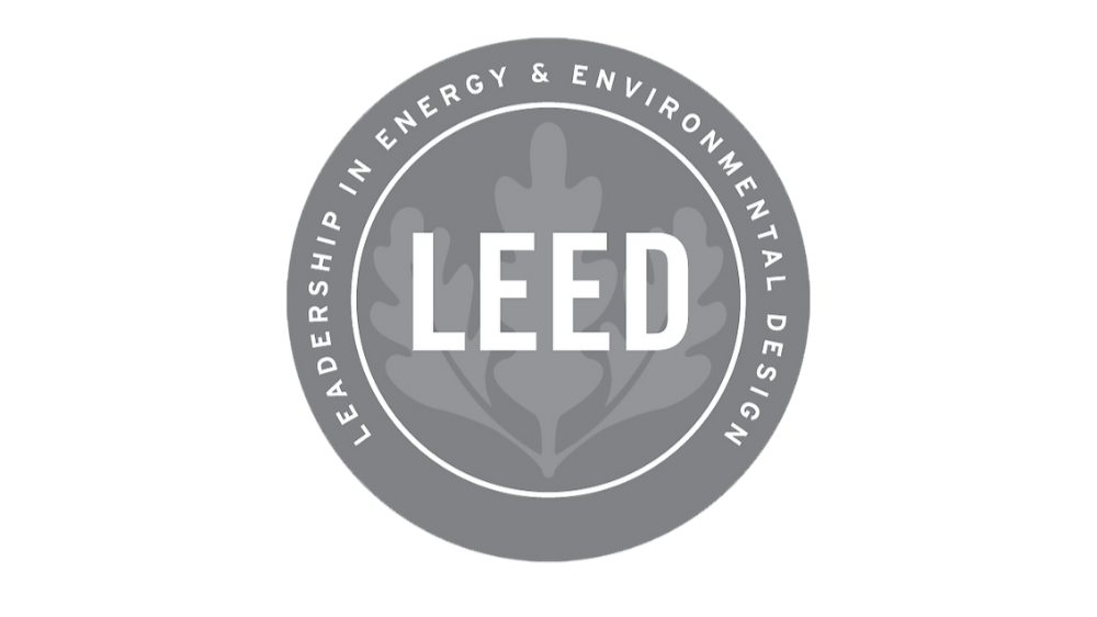 Logotipo en escala de grises de LEED, certificación en energía y diseño ambiental, con un fondo de hoja de árbol