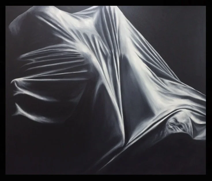 Close-up of a person covered with a sheet, with shadows and folds creating a mysterious shape