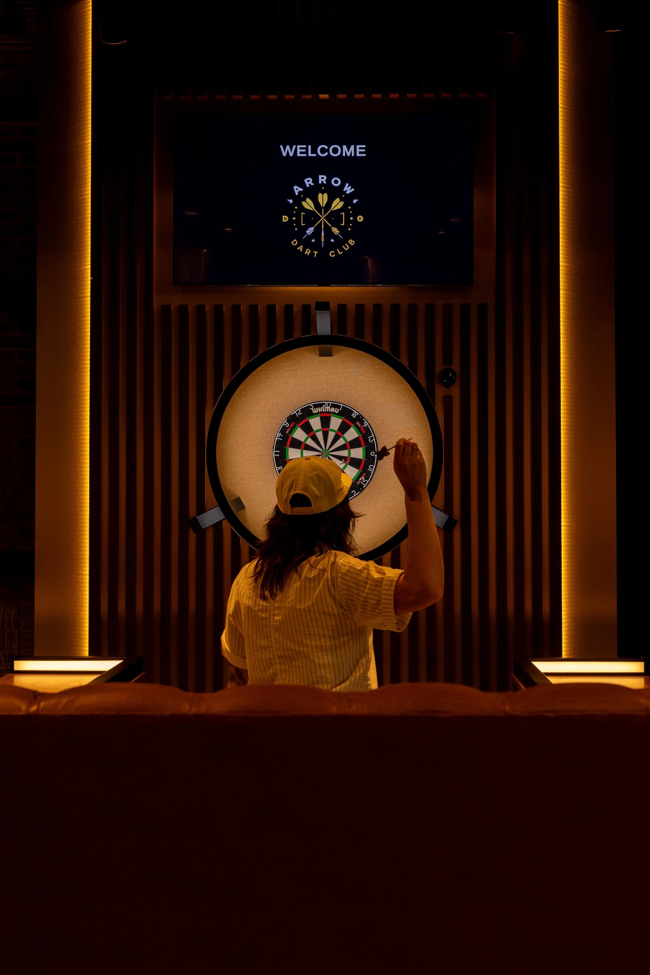 Person Throwing a dart toward a dartboard.