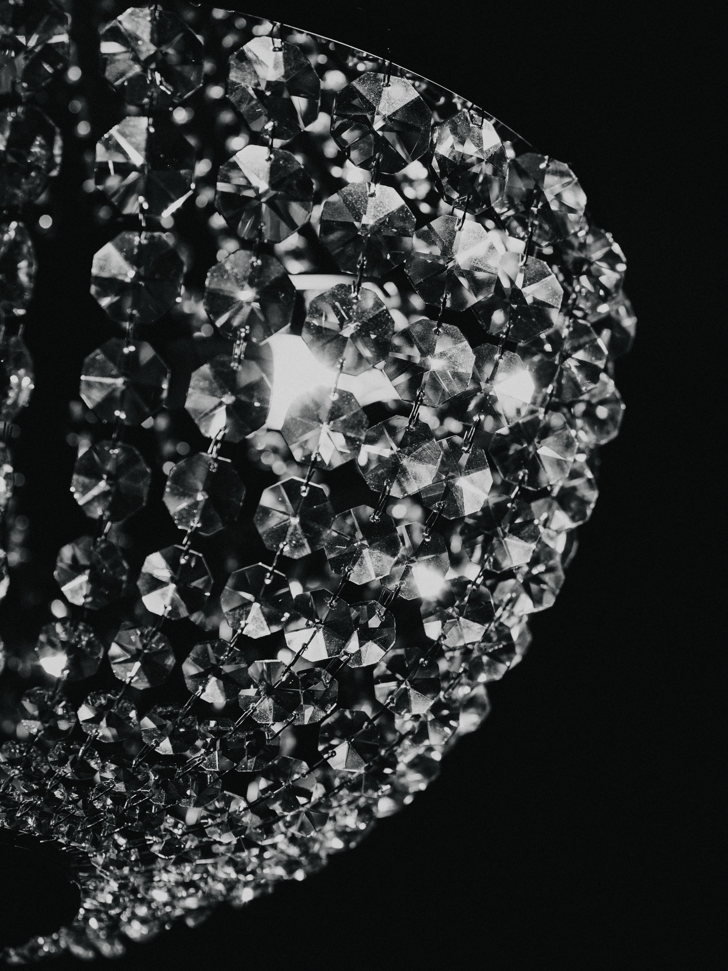 Close-up of a sparkling crystal chandelier with multiple small, faceted crystals reflecting light against a dark background.