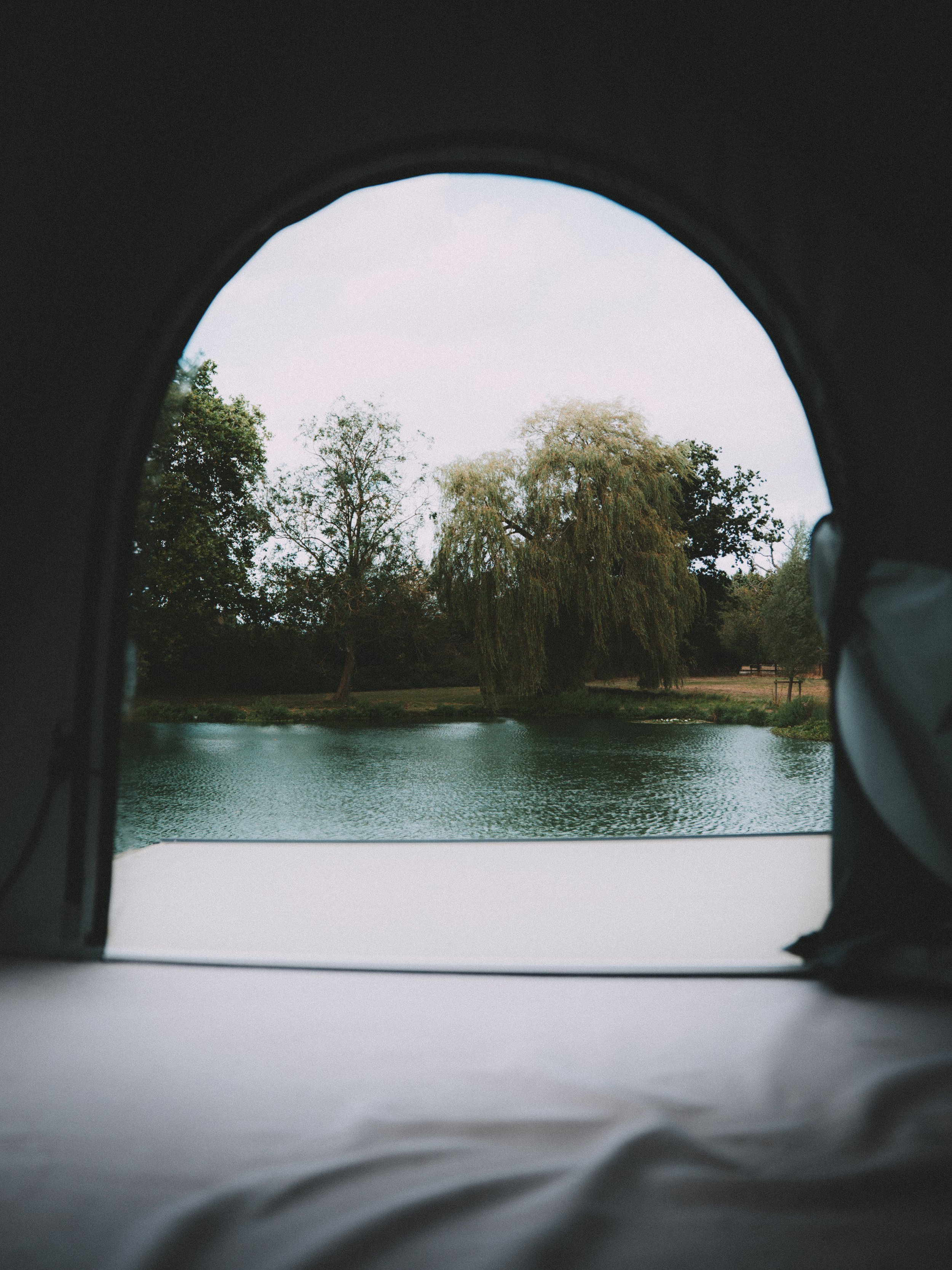 View of a lake and trees through the open flap of a tent.