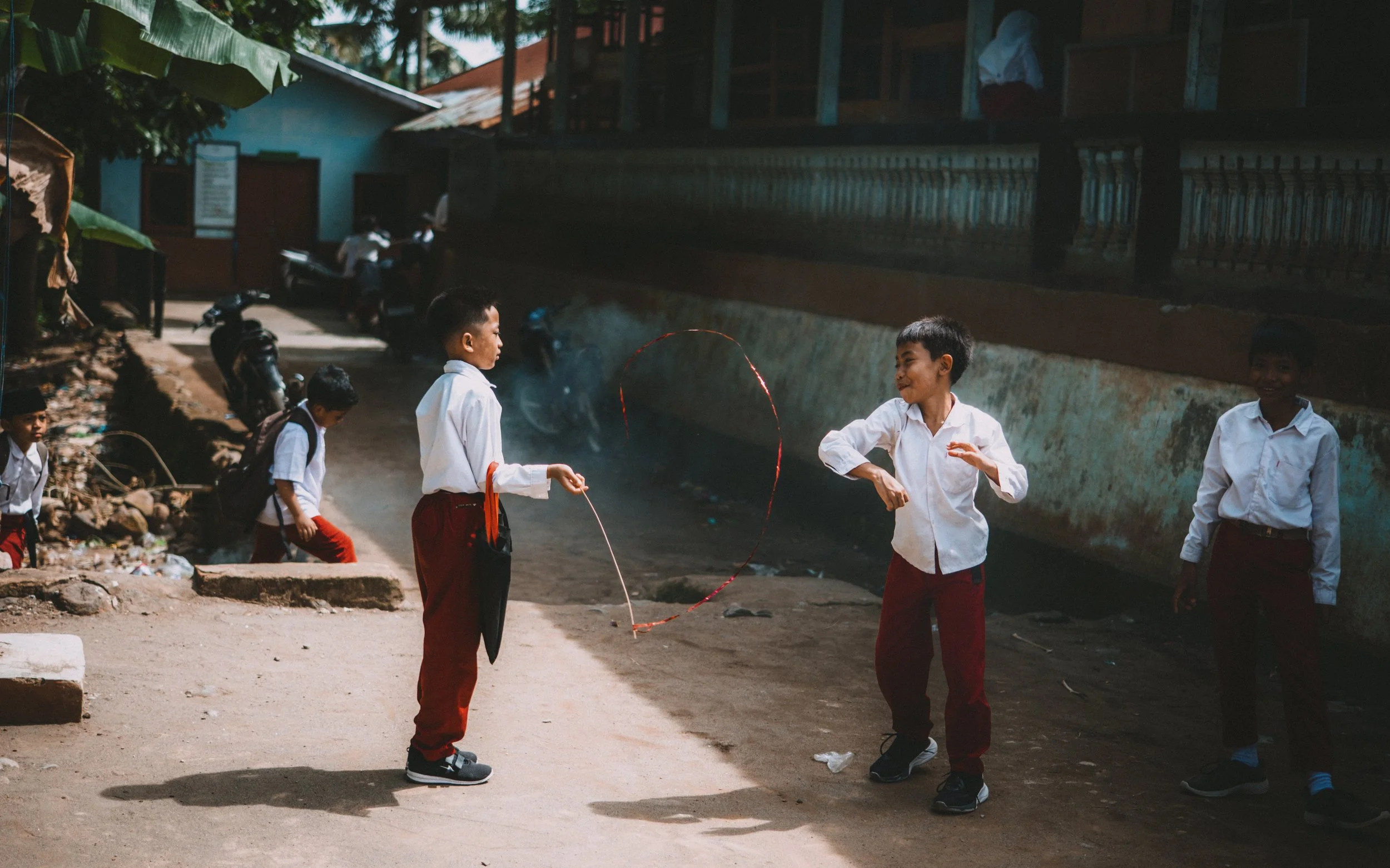 Group of schoolchildren playing with a hula hoop and bubble wand outdoors.