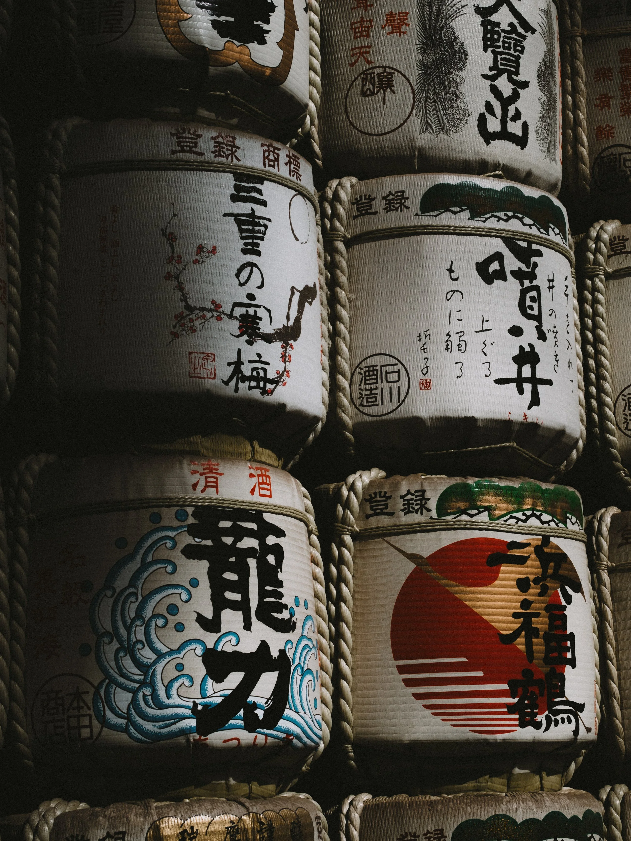 Stacked traditional Japanese sake barrels decorated with calligraphy and artwork.