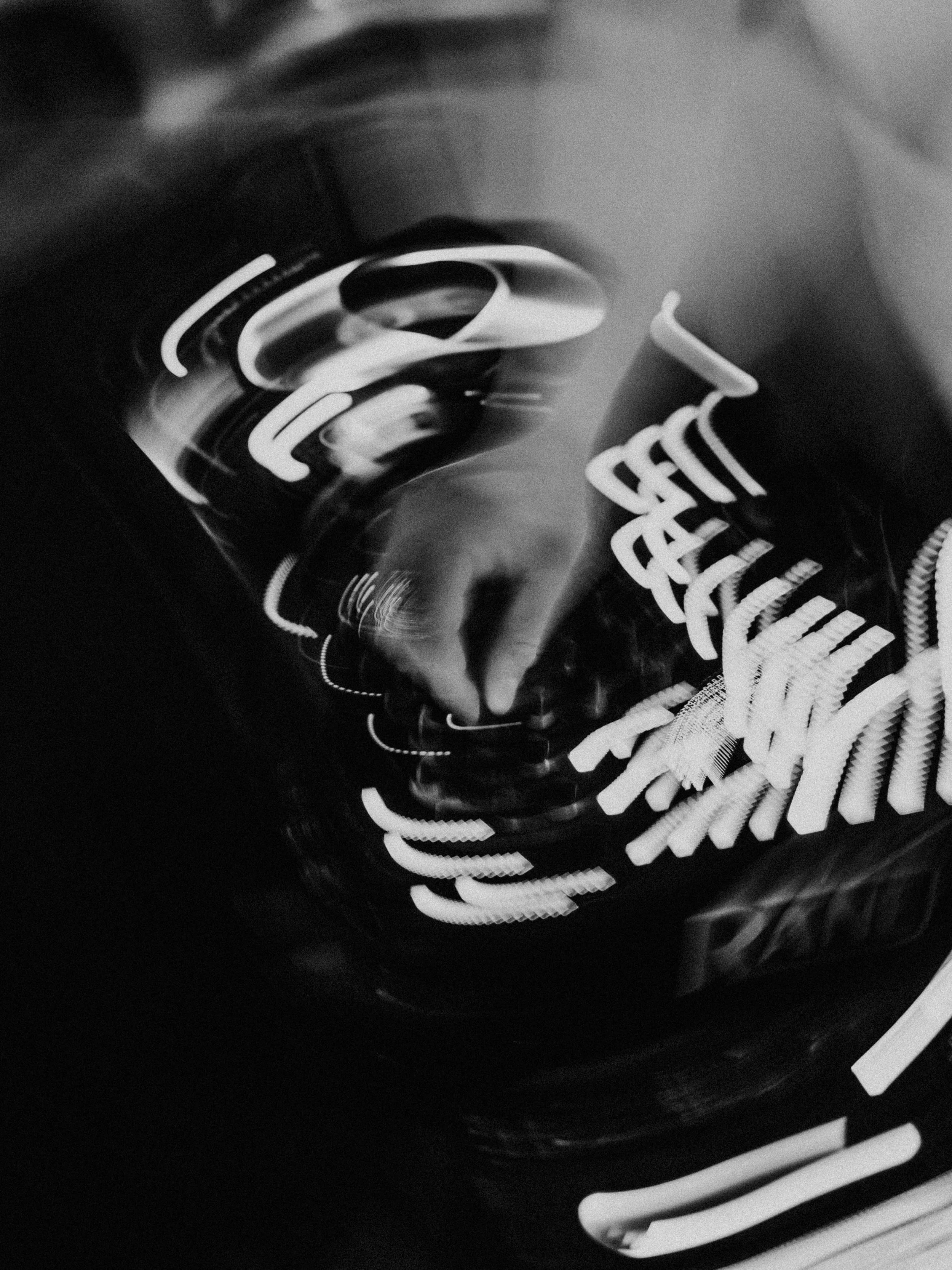 Abstract black and white photo of a soda can with distorted reflections and text.