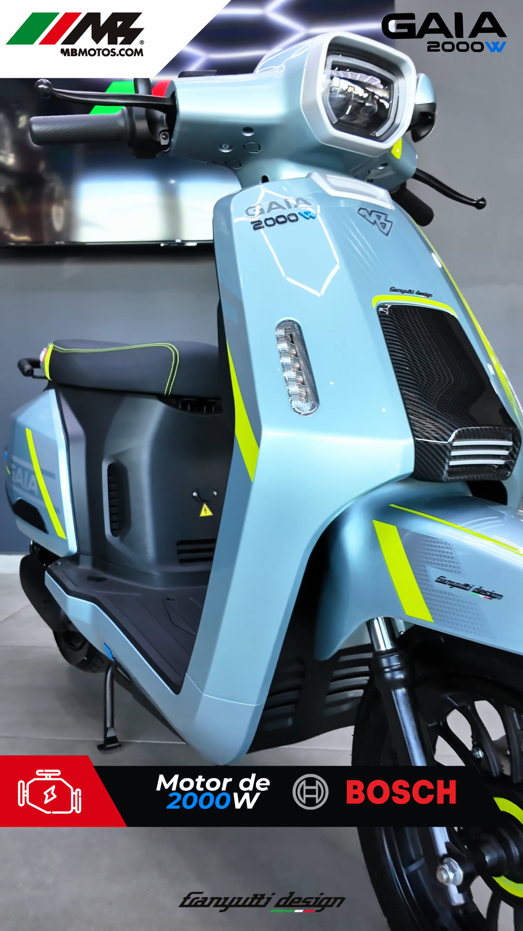Scooter eléctrico de color azul claro con detalles en amarillo neón, marca GAIA, motor de 2000W, logo MB motos y Bosch en el panel frontal, con pantalla digital y espacio para el conductor, exhibido en un entorno de exhibición.