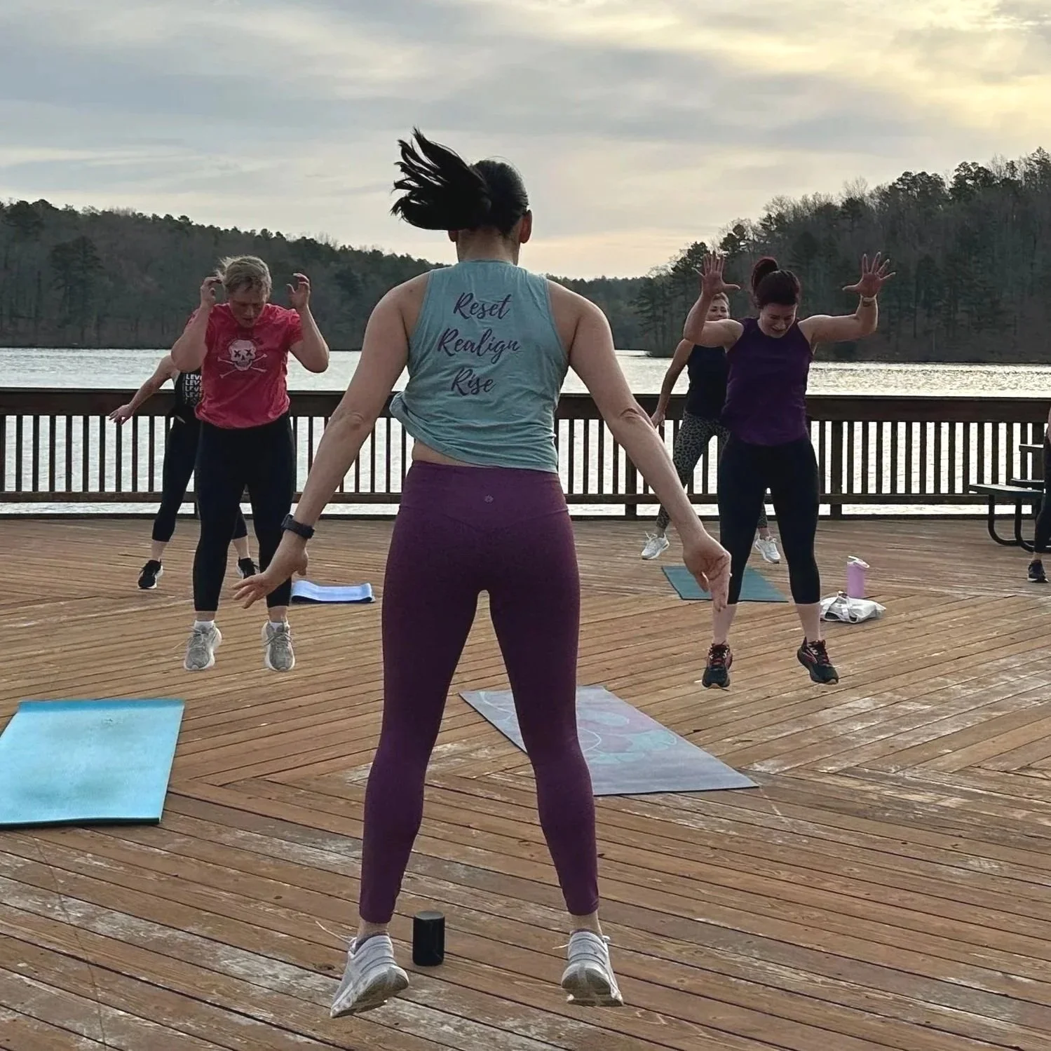 A fitness instructor midjump leading a fitness session during a women's retreat.