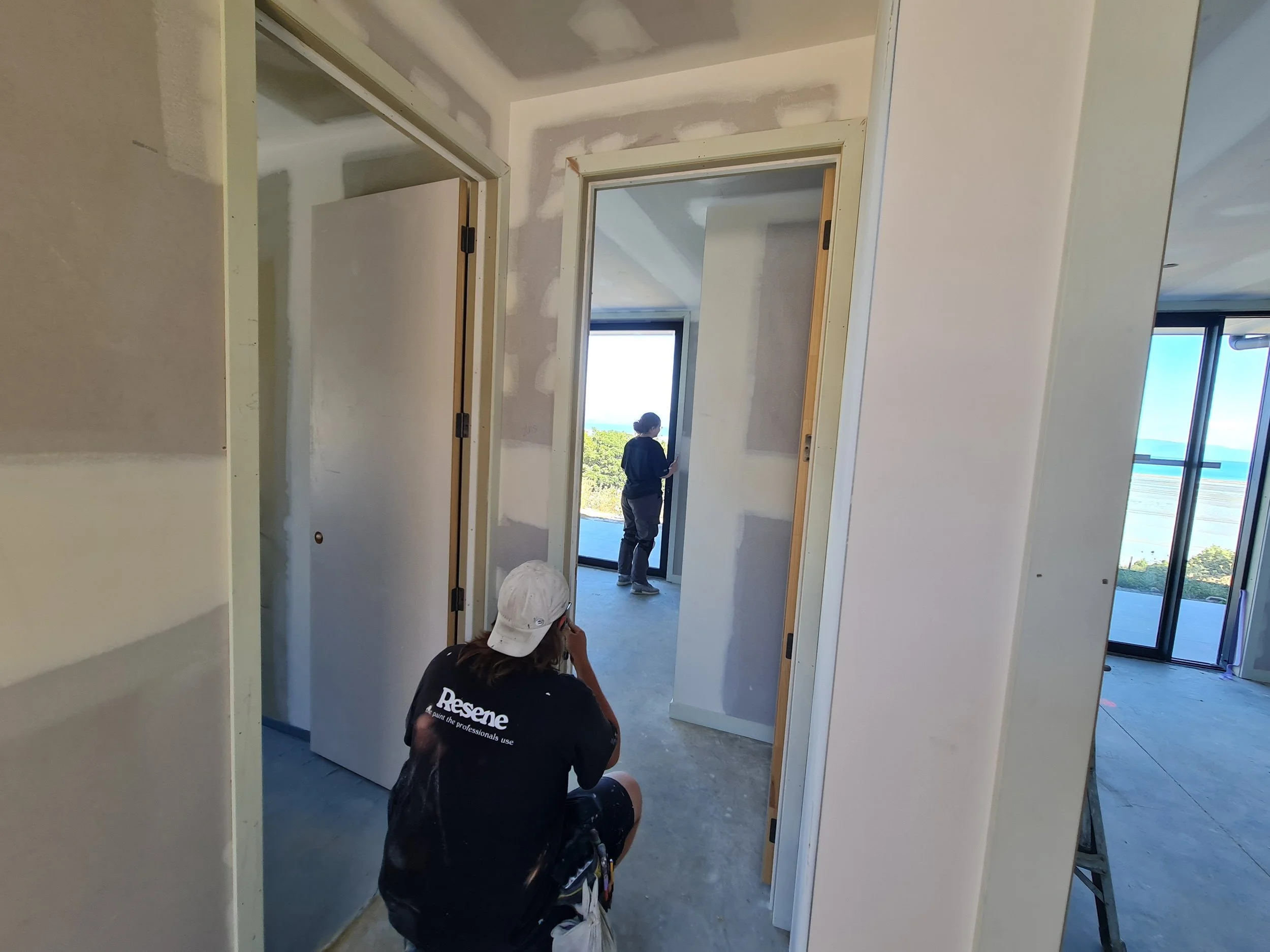 Painters preparing an interior with protected doorways and unfinished plasterboard