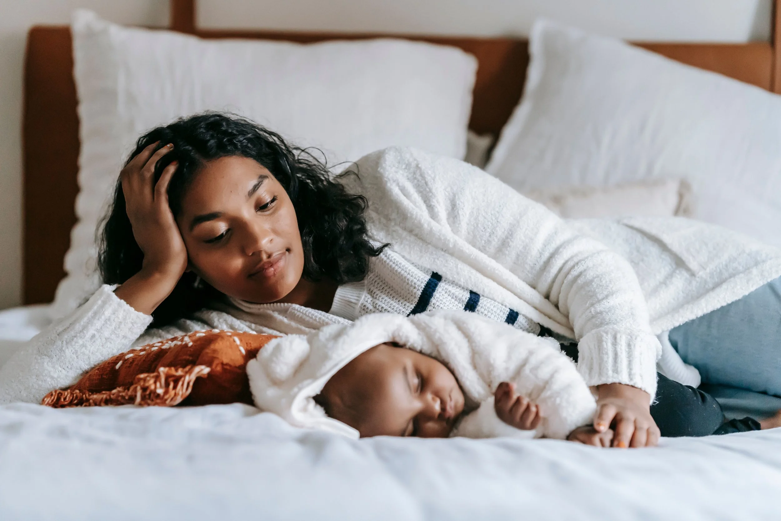 Tired mom laying in bed with sleeping baby