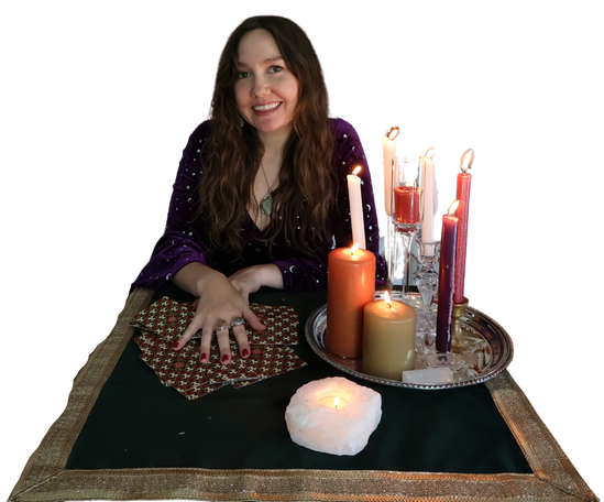 Woman sitting at a table with candles and tarot cards for a reading