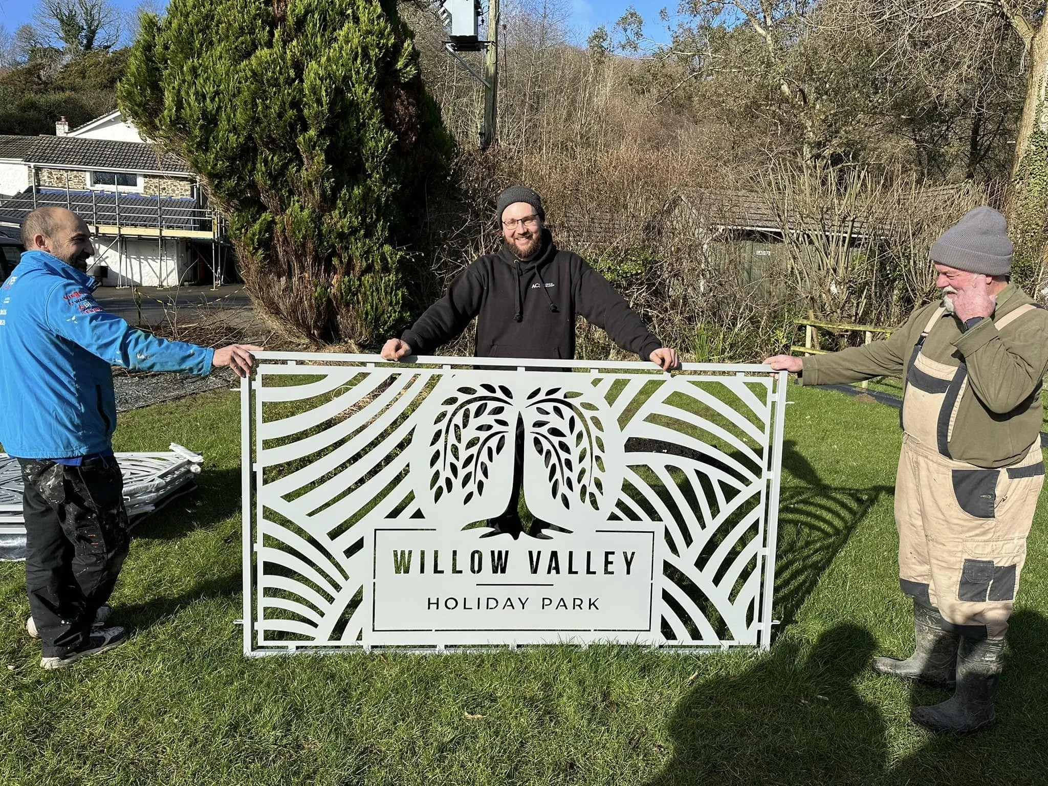 ACS Welding & Fabrication CEO standing with a completed CNC Plasma Cut sign