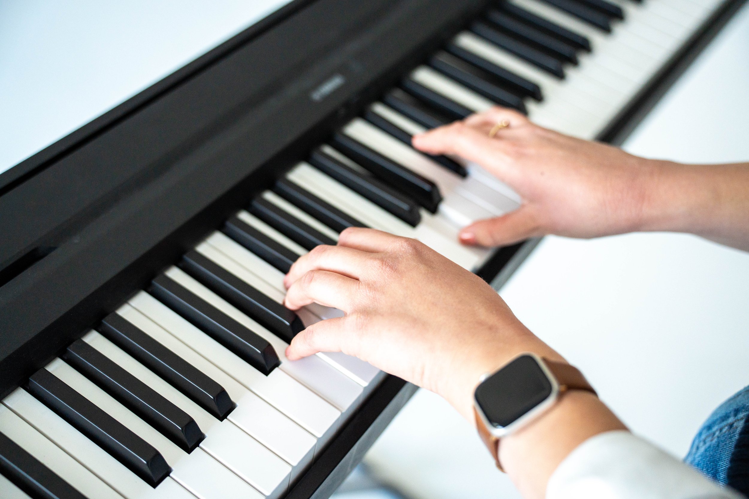A close-up shot of a keyboard with two hands playing it