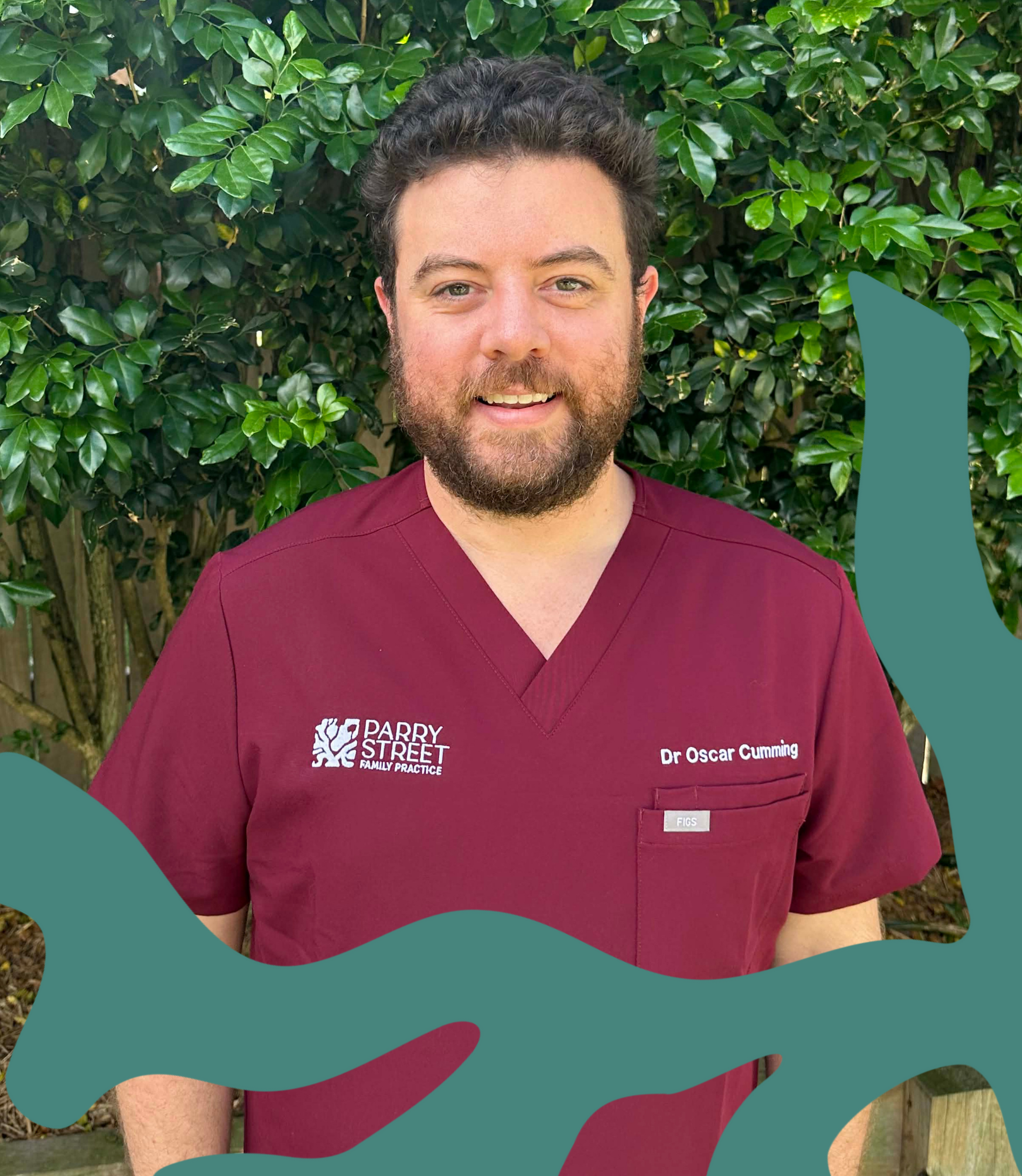 A man in maroon medical scrubs standing outdoors in front of green foliage, smiling at the camera. His scrubs have the text "Parry Street Family Practice" on the left side and "Dr Oscar Cumming" on the right side.