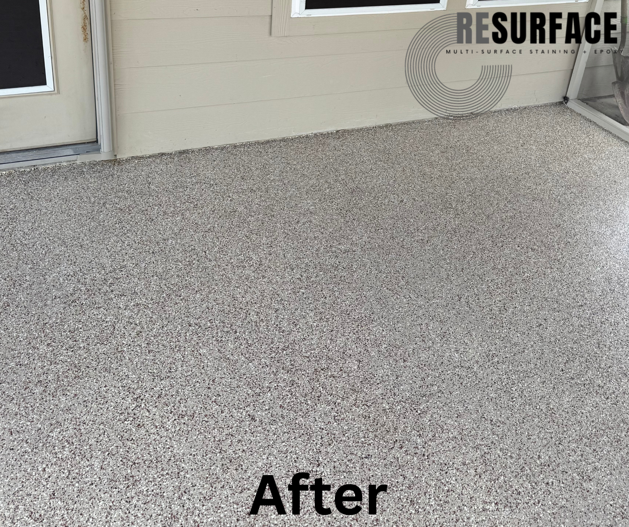 A freshly coated outdoor patio surface with a textured, multi-colored epoxy finish, shown after application, next to beige or light-colored house siding and a glass sliding door.