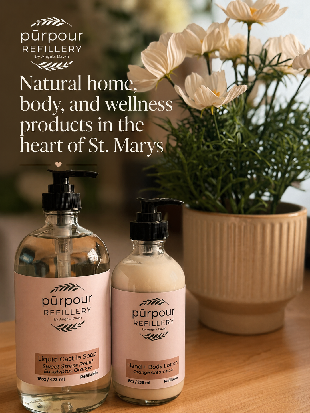 a bottle of hand soap and lotion on a counter top with flowers in the background. A text overlay says "Natural home, body, and wellness products in the hear of St.Marys"