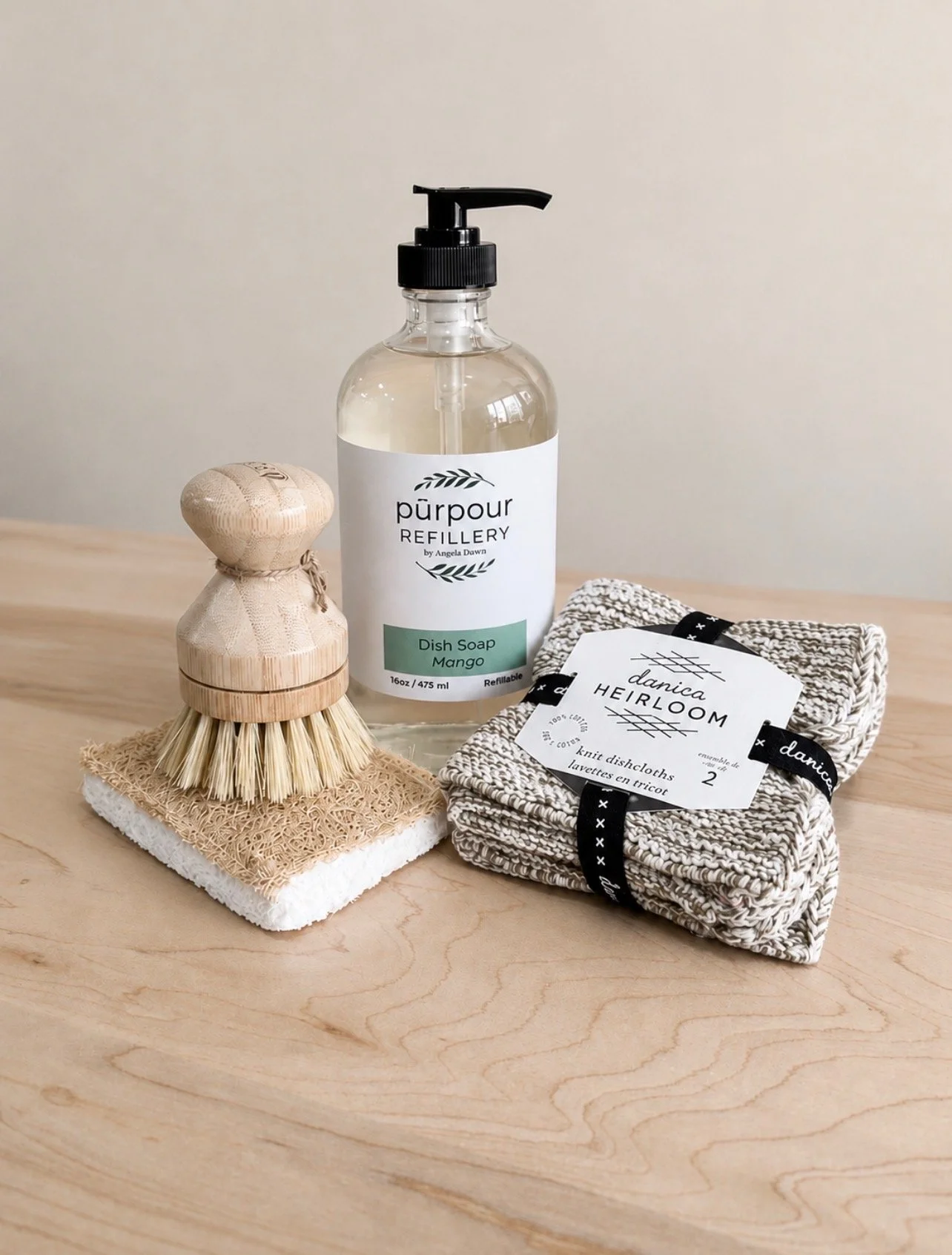 a refillable bottle of dish soap, a dish scrubber know (with replaceable scrubbing knob), cellulose dish soap, and a set of 2 dish cloths