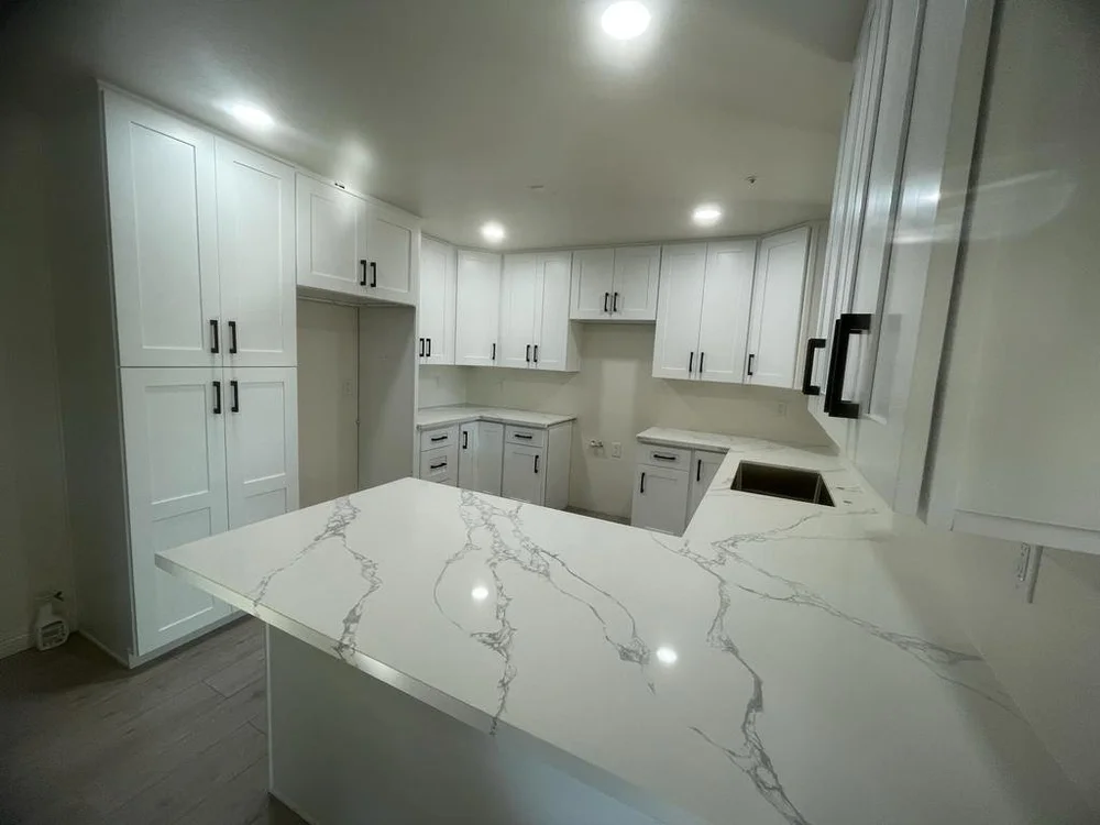 Remodeled white kitchen with quartz counters by Imperium Strategies Group