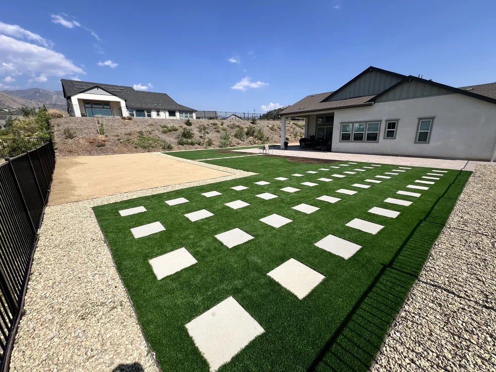Backyard with artificial turf, paver stepping stones and gravel borders