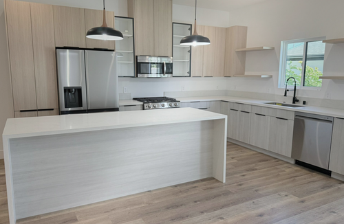 Modern kitchen with island, light oak floors and stainless appliances