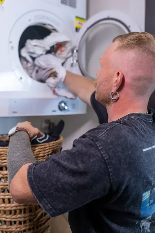 NDIS support worker providing domestic assistance by helping with laundry at home.