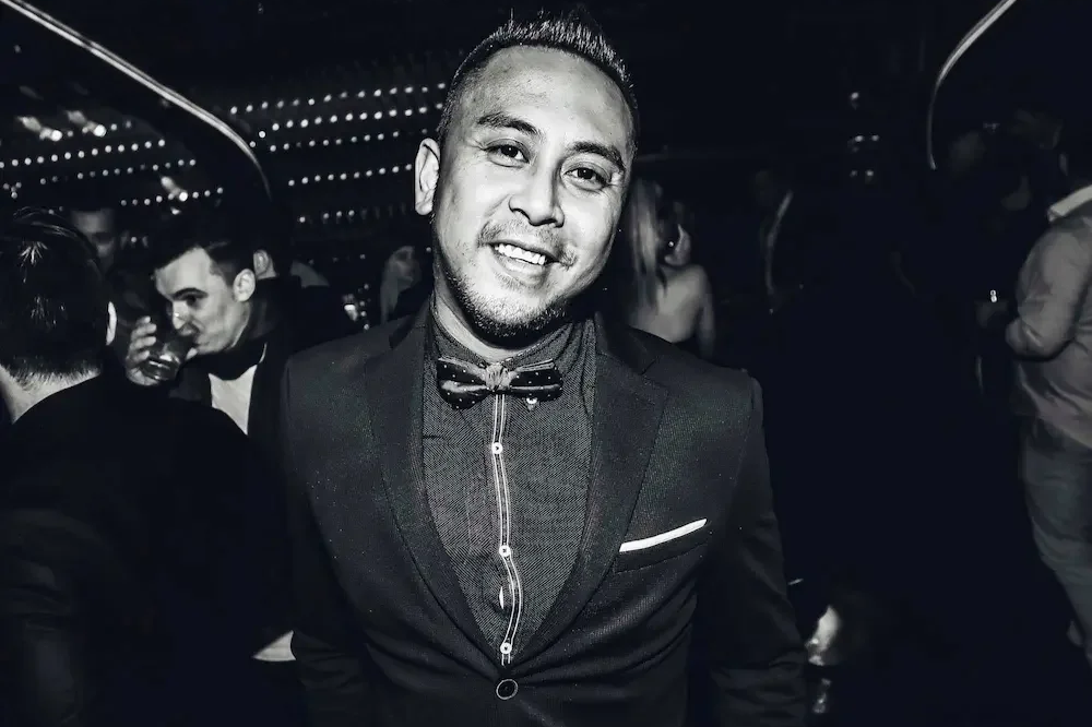 A smiling man in a tuxedo and bow tie at a party or event