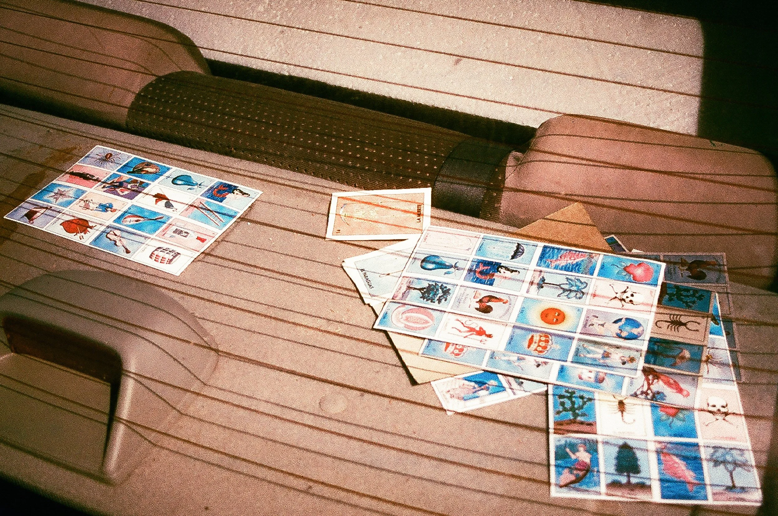 Mexican lottery cards scattered on a surface, highlighting 'La Muerte' (The Death) card as the finale. 35 mm color film.