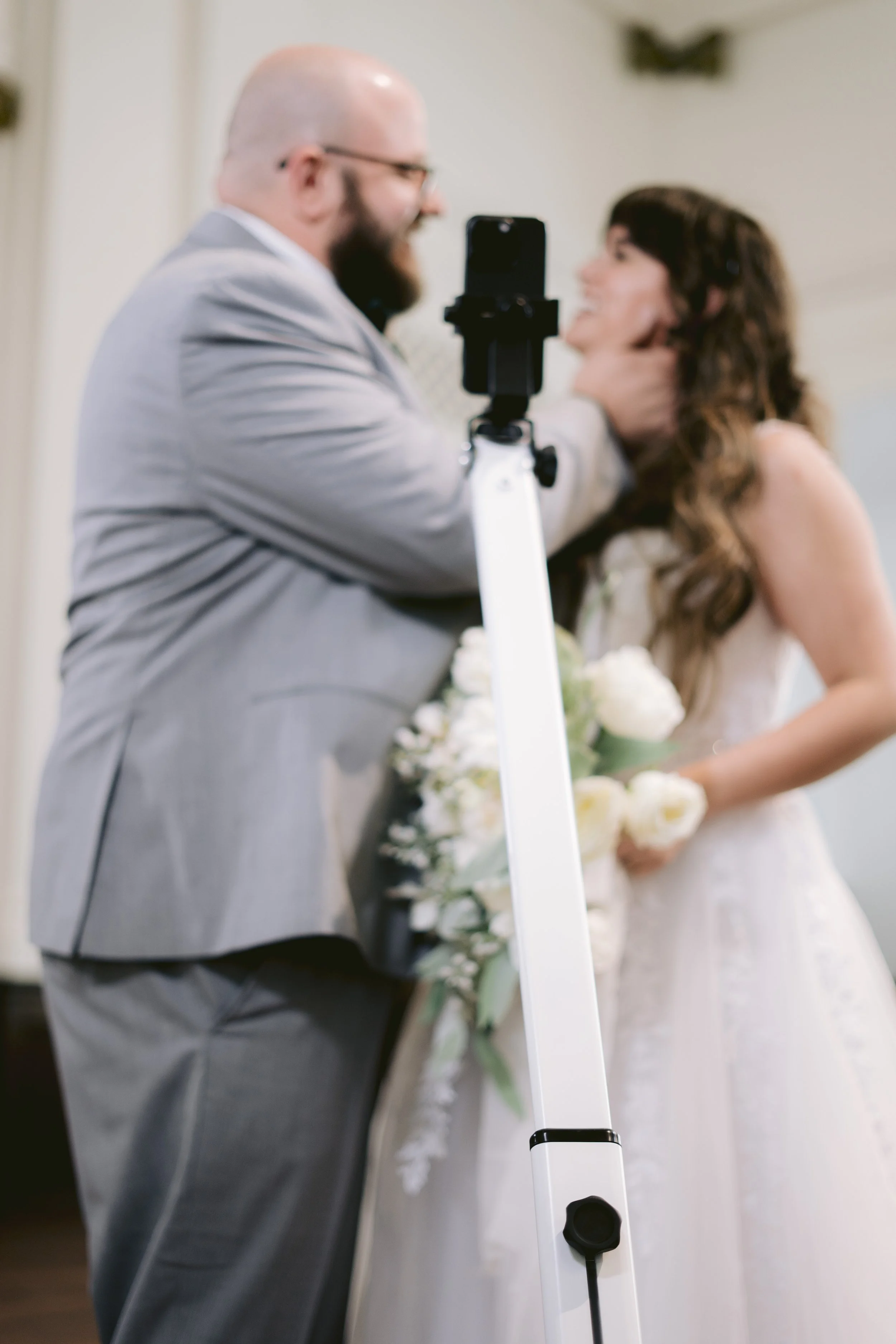 a bride and groom using a 360 photo booth for their wedding day. bride is holding a bouquet