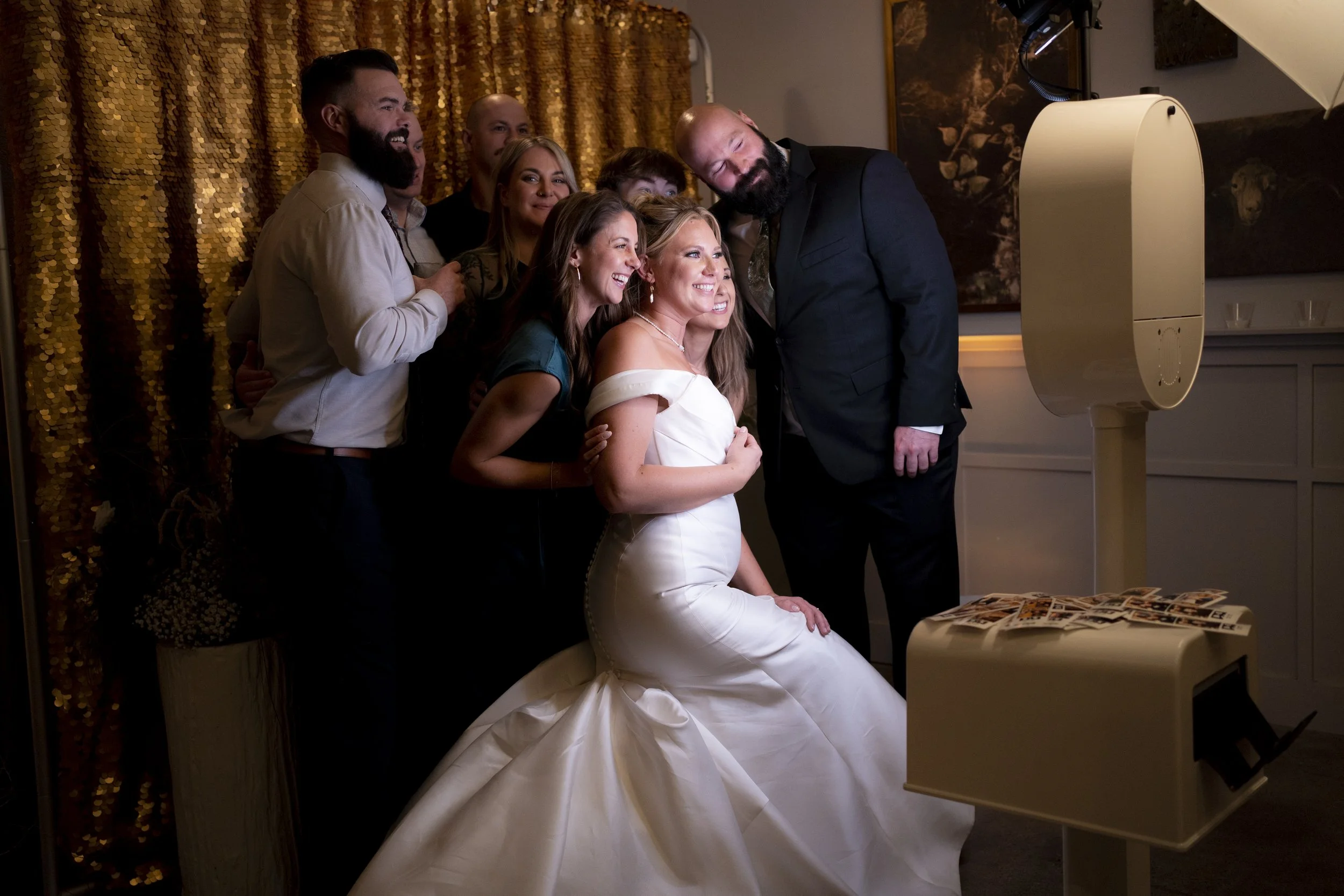 A bride and groom taking a photo with friends or family in a photo booth at a wedding reception.