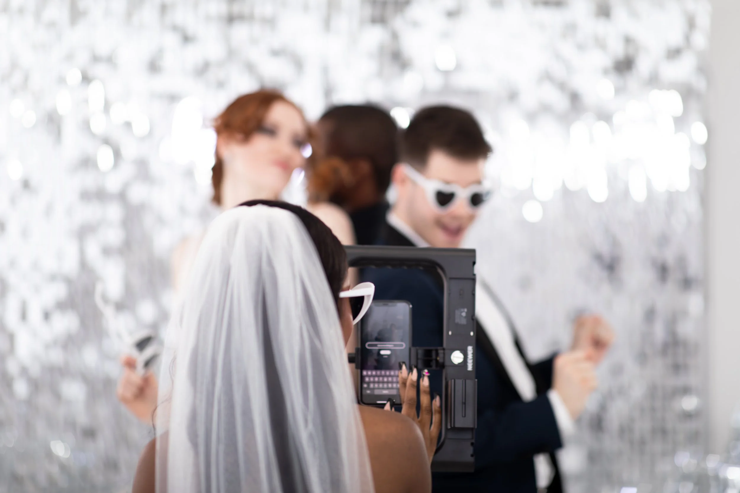 a group of people taking a video on a 360 photo booth with the bride taking information