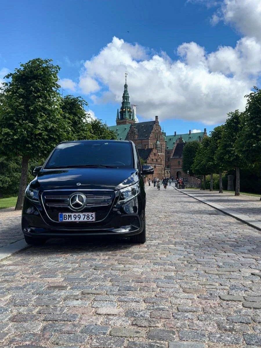 Luxury Mercedes van parked in front of Frederiksborg Castle, ready for private transfers with 24K Transfers