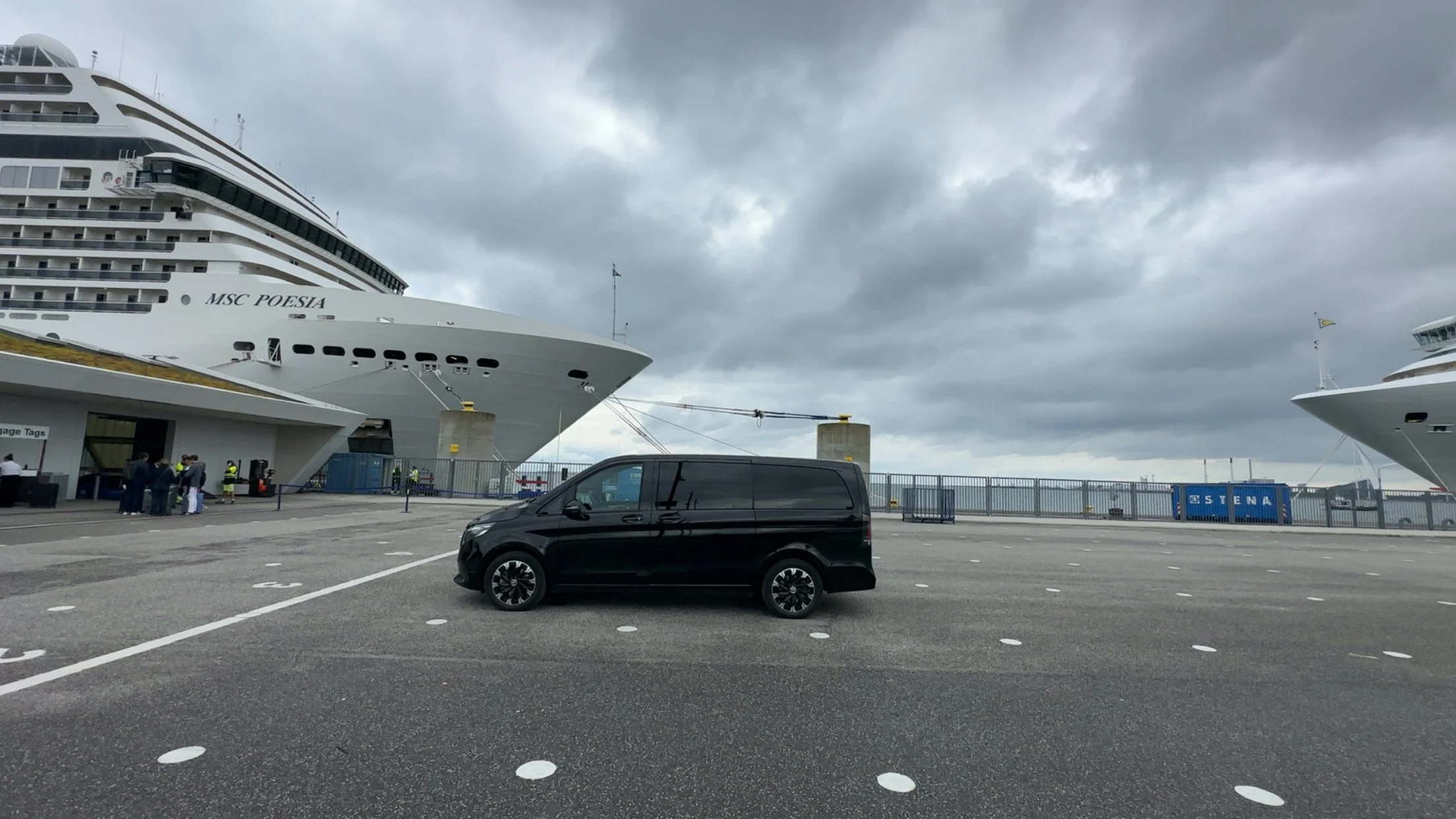 A premium black Mercedes van parked in front of cruise ship at copenhagen cruise terminal.