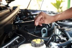 A person's hand adding oil to a car engine.