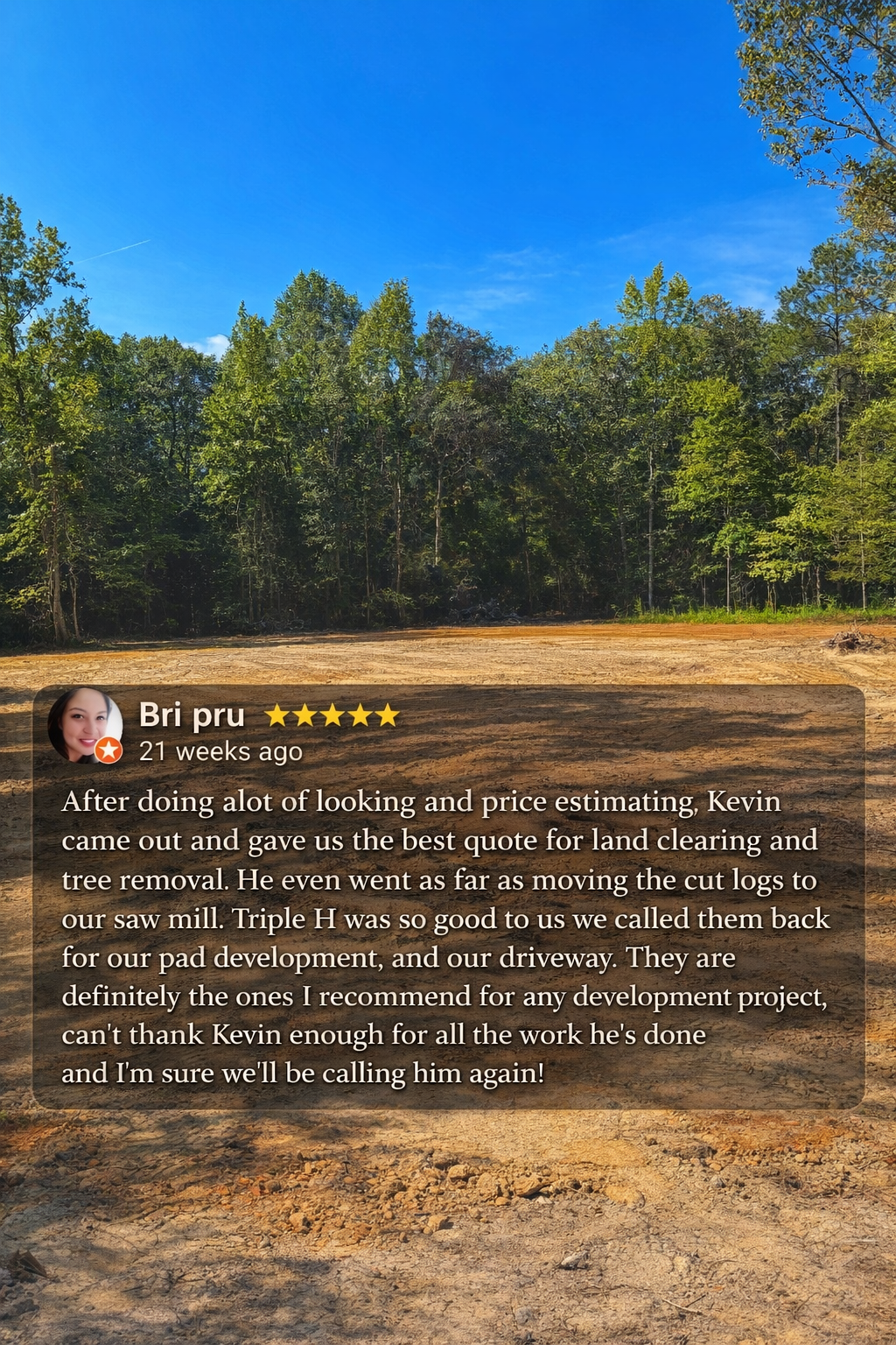 A cleared land area with brown soil, surrounded by a dense green forest under a bright blue sky.