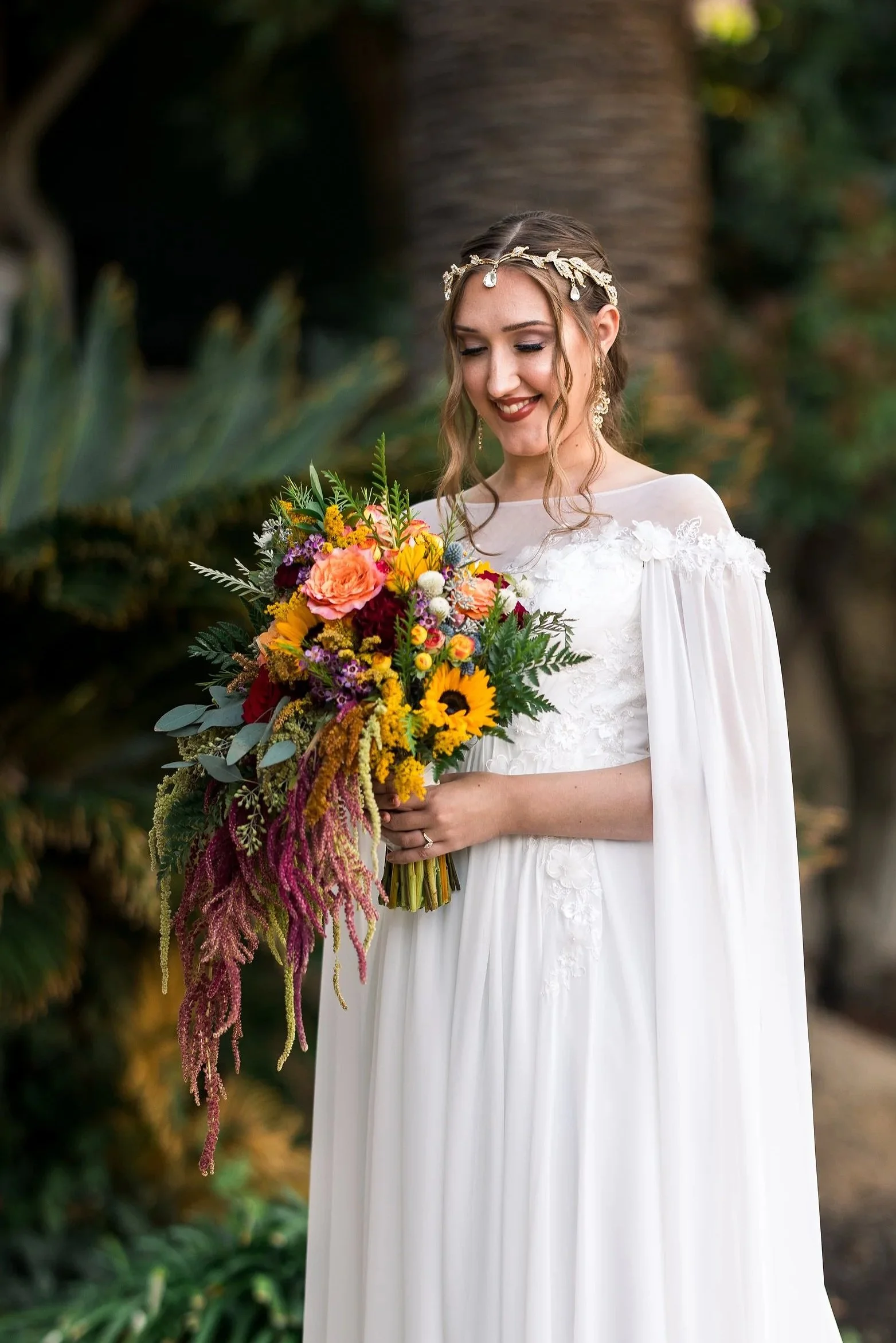 Image of a bride holder her bouquet with sunflowers, roses Amaranthus, and eucalyptus.