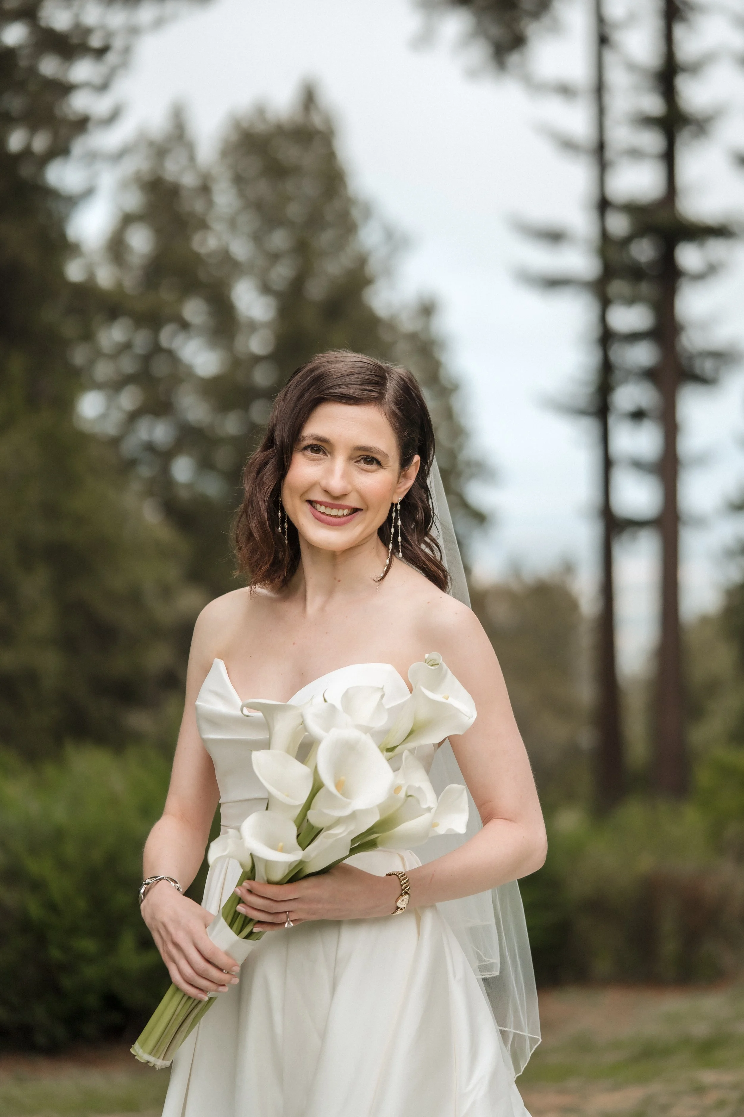Bride holder her bridal bouquet of all white long stem calla lilies.
