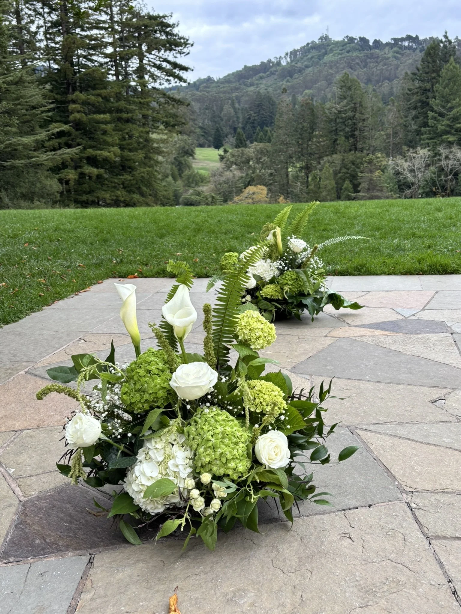 Grounded ceremony flower arrangements of white and green. Roses, hydrangea, calla lilies, and amaranthus.