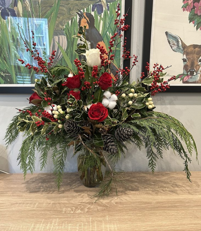 Christmas holiday flower arrangement with white and red roses, pine comes and holiday greenery