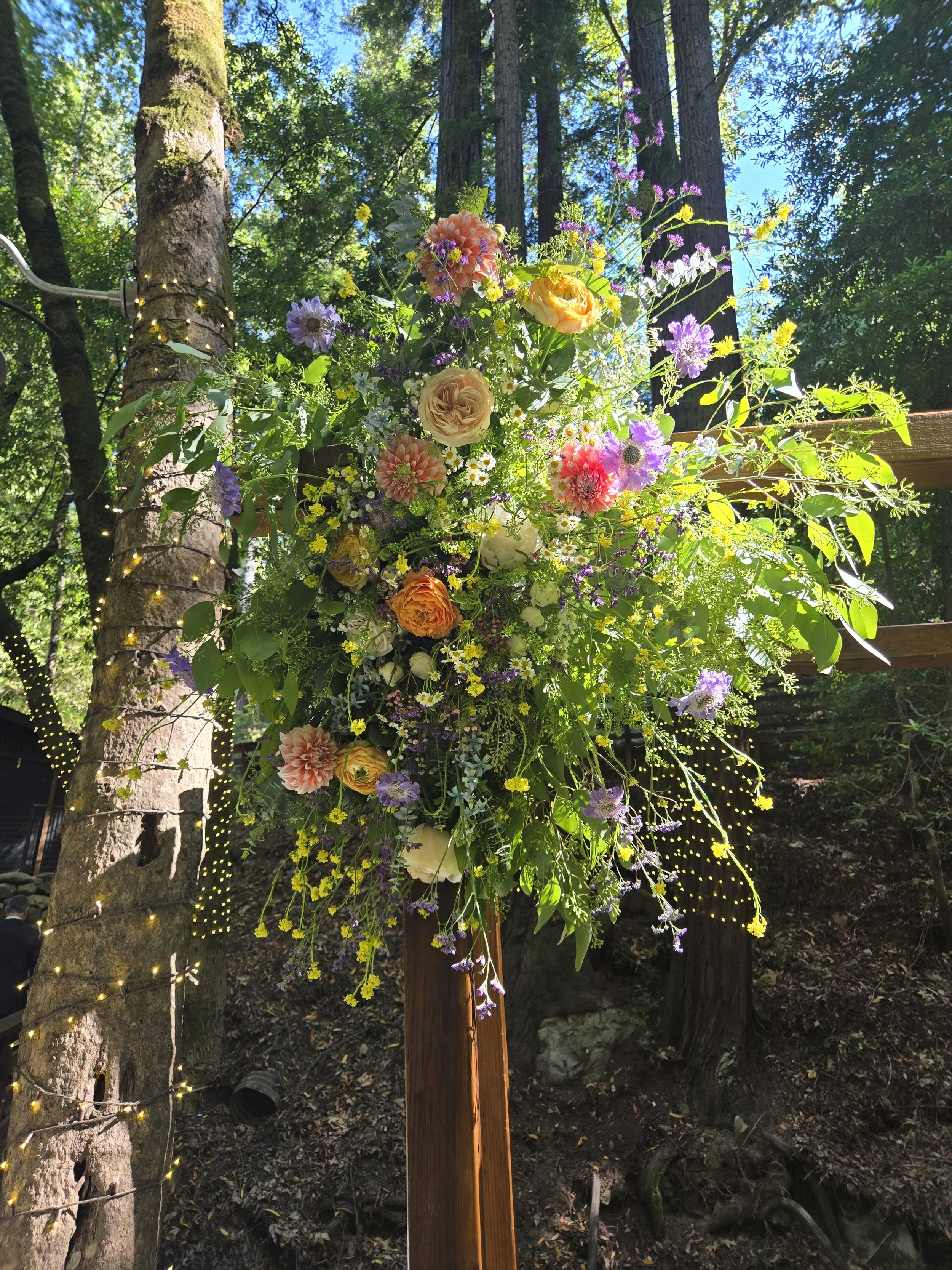 Image of an arch flower arrangement of summertime wild flowers and colors.