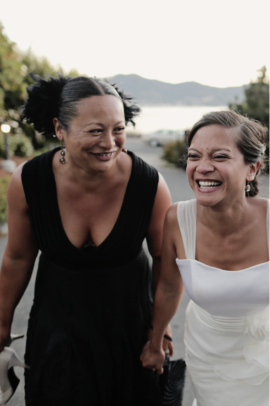 Wedding planner in black laughing with bride in white.