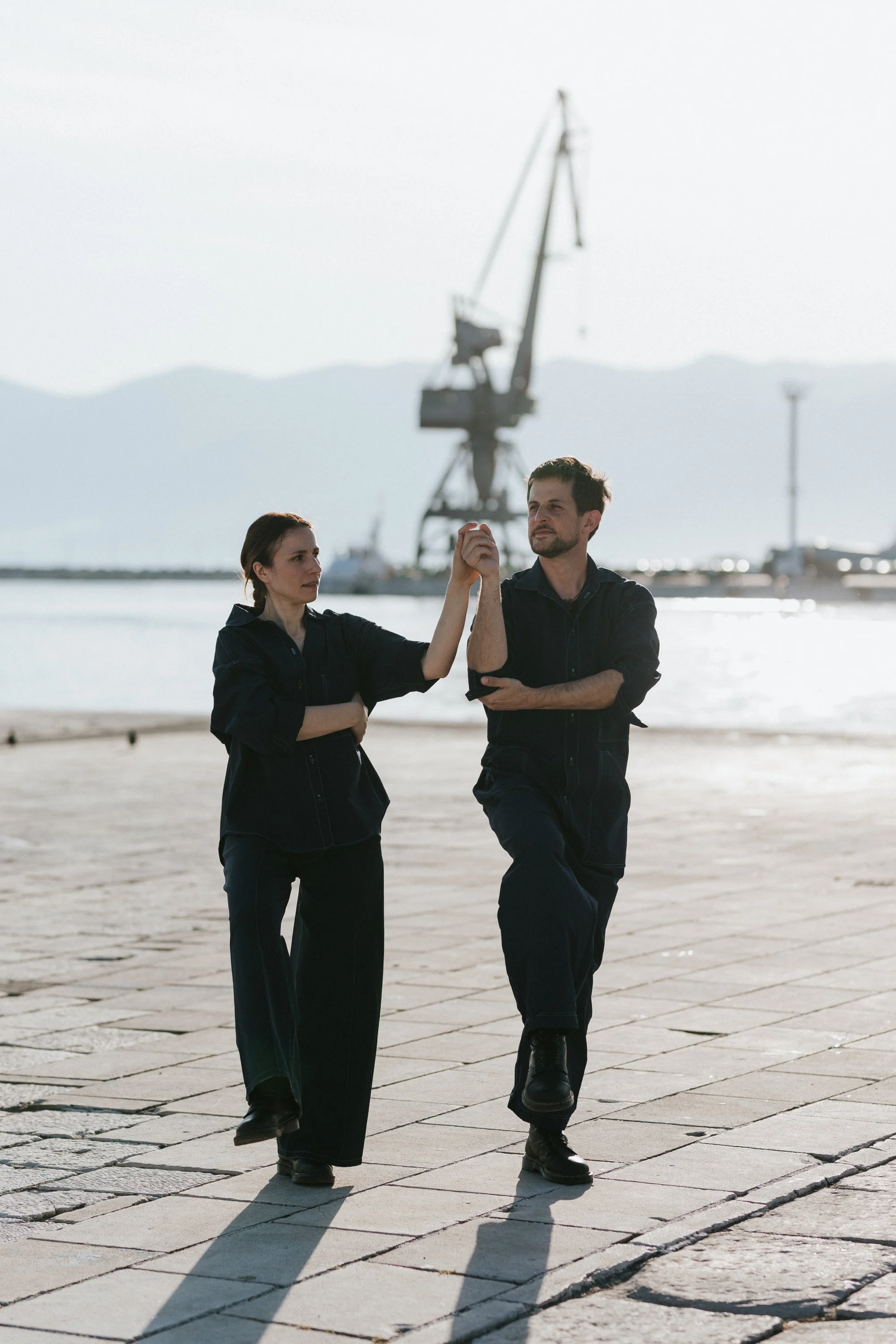 Seagulls Fly Early: two performers on a harbour quay, a crane behind them