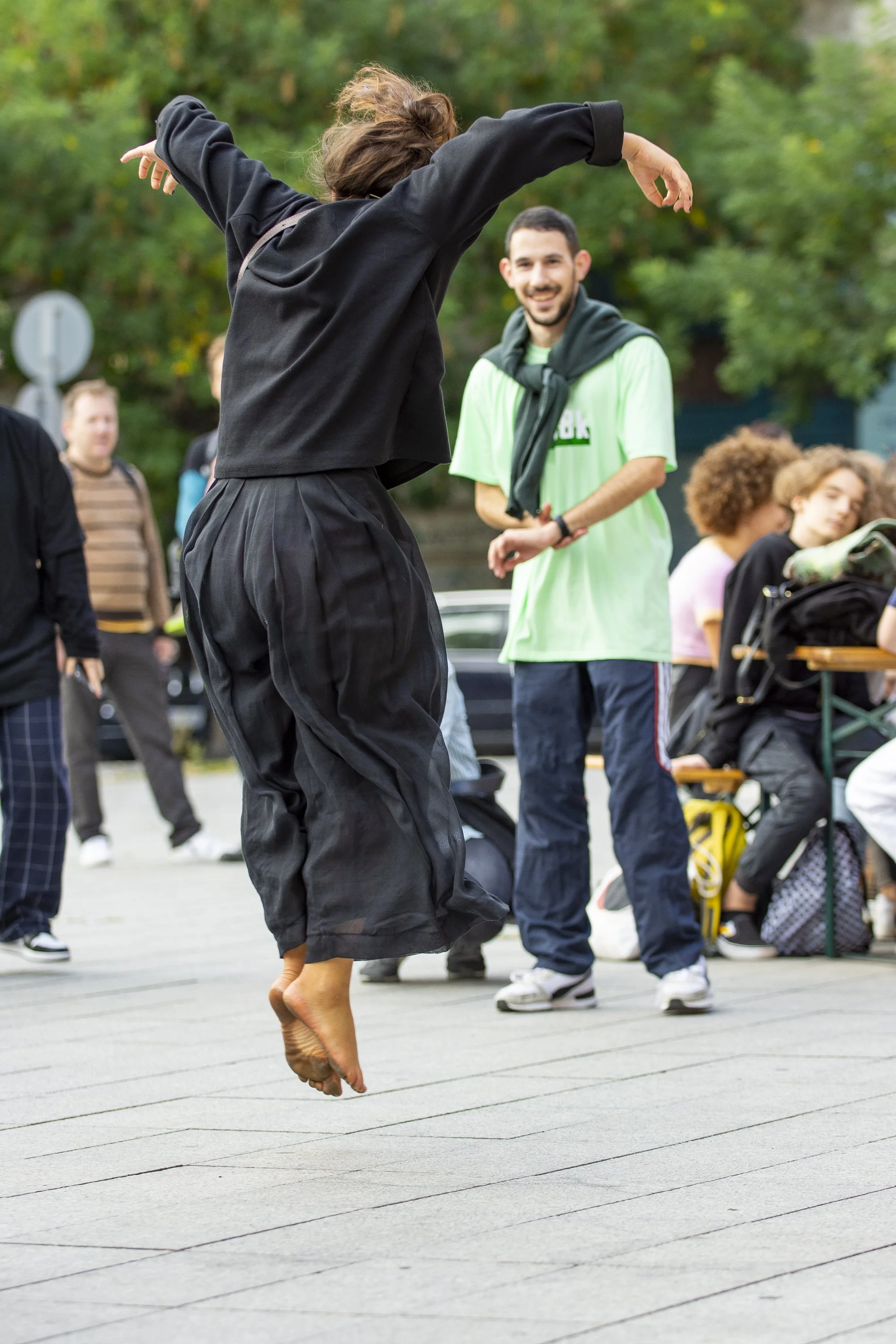 Join the Dance!: a dancer mid-jump in a public square as people watch