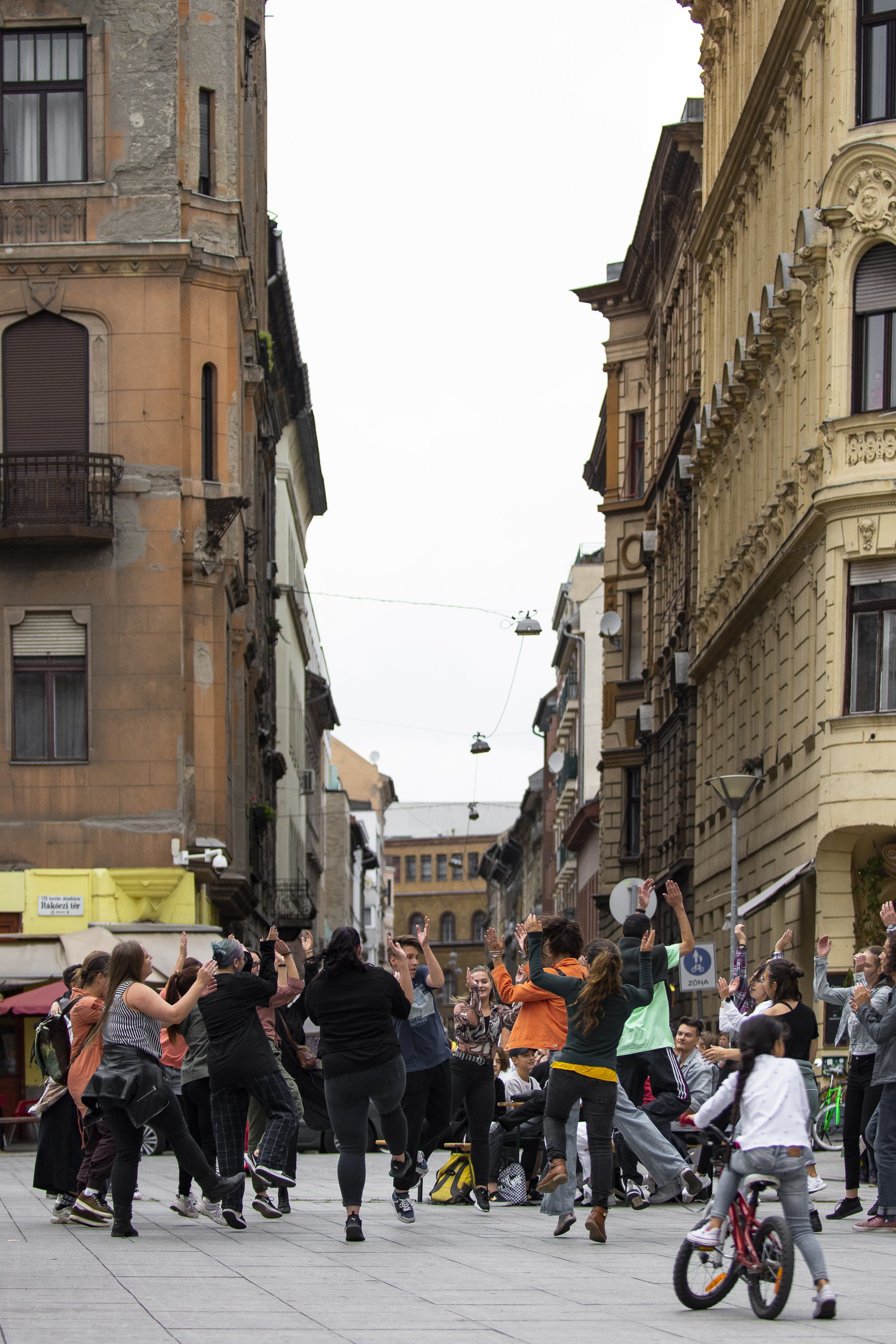 Join the Dance!: a crowd dancing in a city street between historic buildings