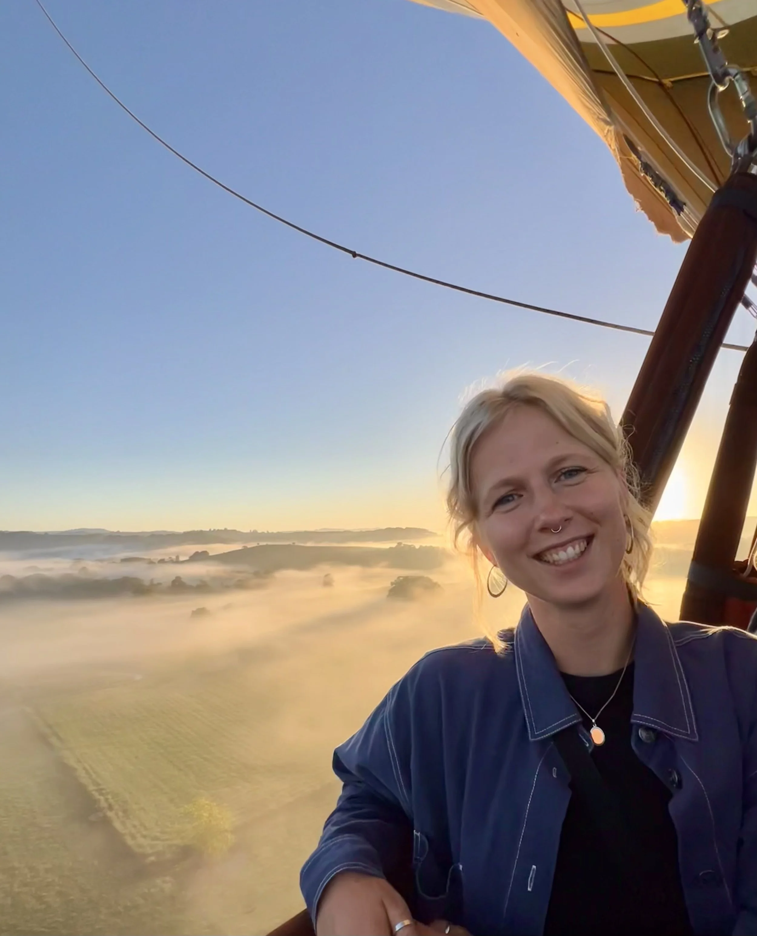 Grundlæggeren af PERSPEKTIV smilende i en luftballon med udsigt over marker, træer, tåge og solopgang – oplev rejser til Nepal, Vietnam og Sri Lanka fyldt med eventyr og unikke rejseoplevelser.