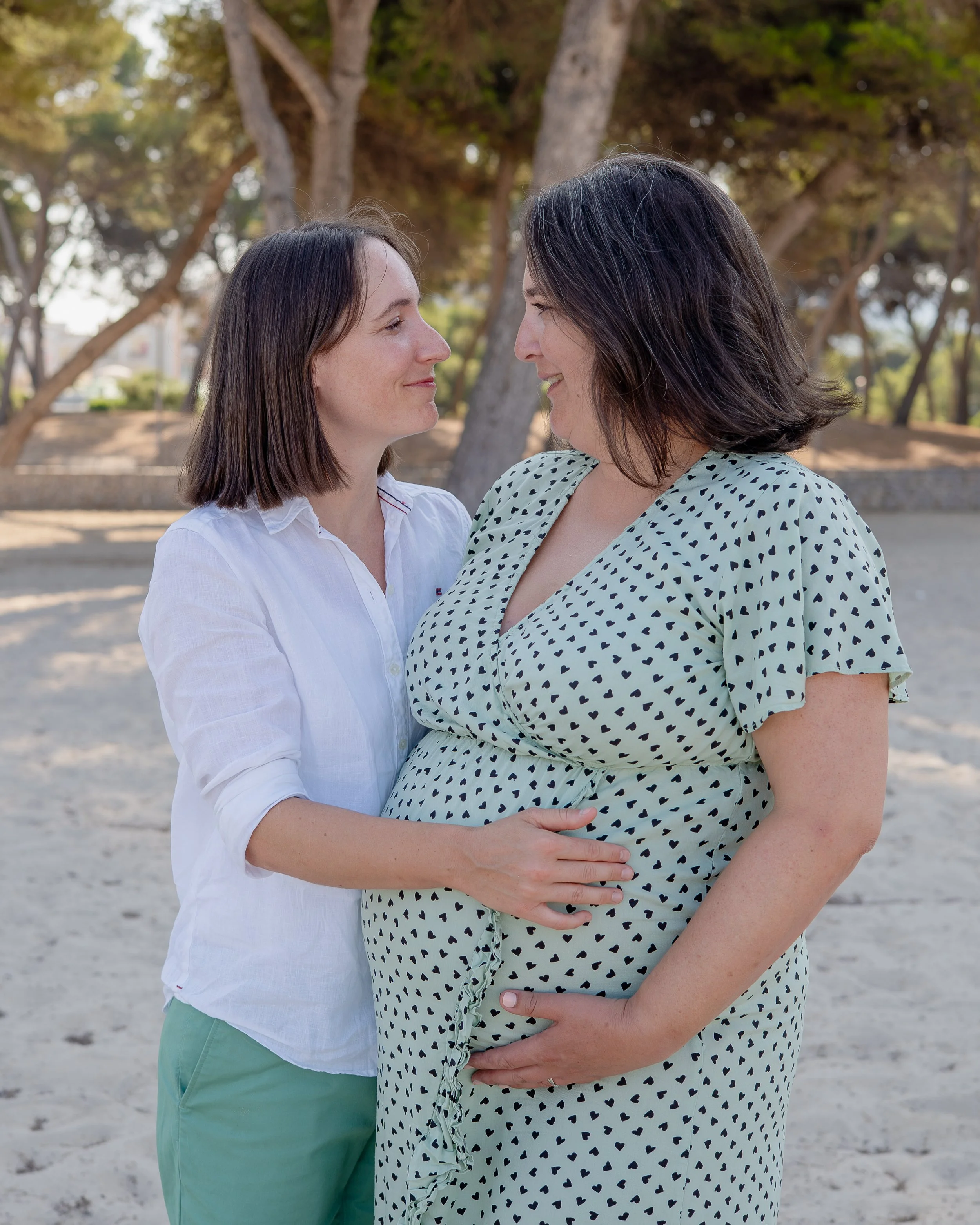 Zwangerschapsshoot op Mallorca met een lesbisch stel dat elkaar liefdevol aankijkt en samen uitkijkt naar de komst van hun baby tijdens een ontspannen en intieme fotosessie.