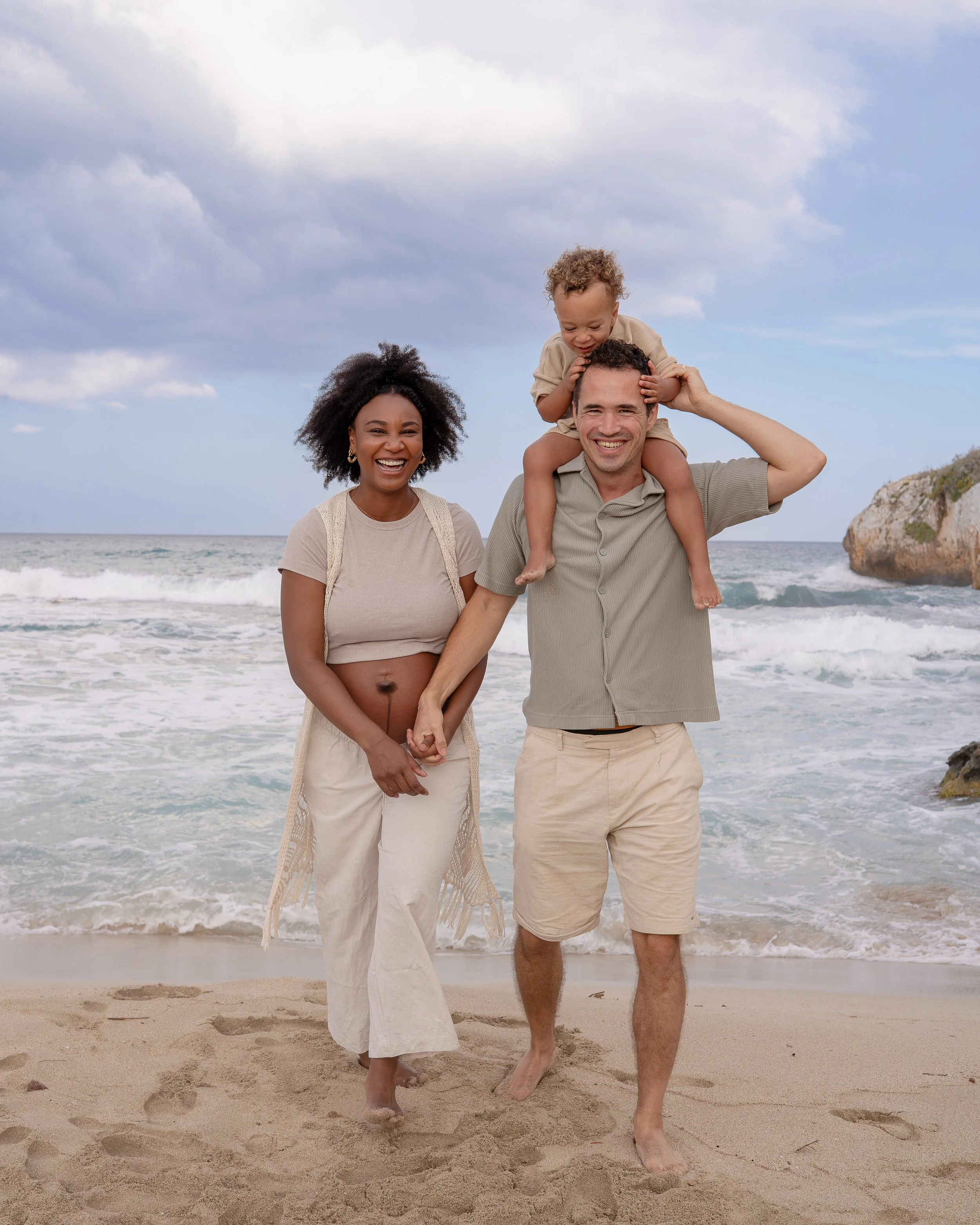 Zwangerschapsshoot op Mallorca op het strand, met aanstaande ouders en hun zoontje die samen genieten van een liefdevol familiemoment tijdens hun vakantie.